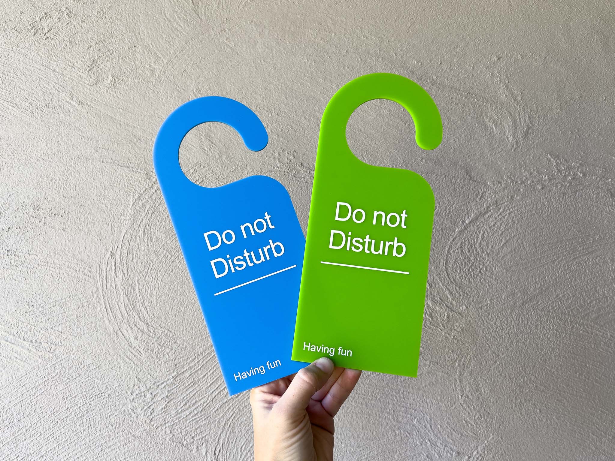 Two brightly coloured "Do not Disturb" acrylic door hangers in blue and lime green.