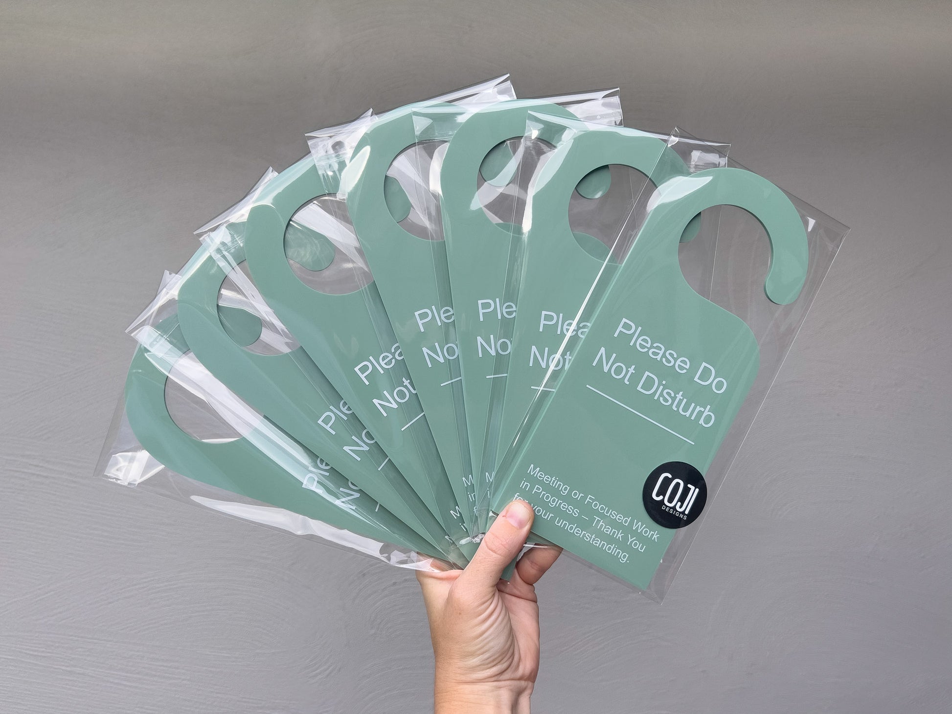 Collection of sage green personalised 'Please Do Not Disturb' UV printed acrylic door hangers.