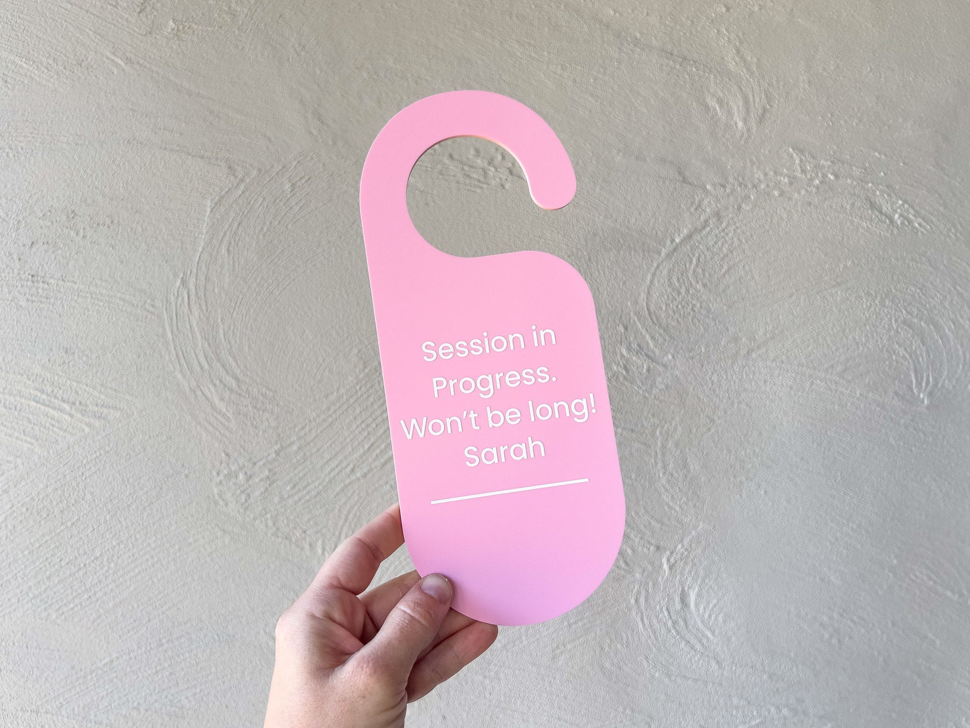 Light pink custom UV printed door hanger to display for waiting customers in a busy studio.
