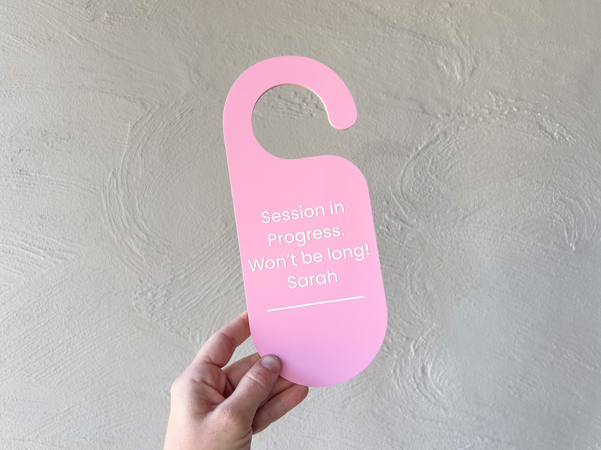 Light pink custom UV printed door hanger to display for waiting customers in a busy studio.
