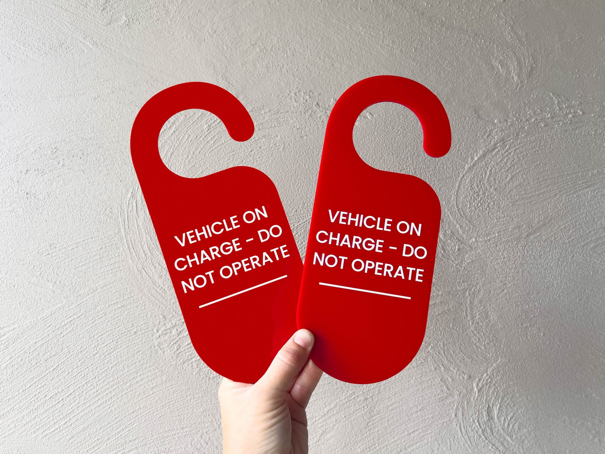 Custom printed red rounded edge hangers for hanging in a vehicle. The hangers read 'VEHICLE ON CHARGE - DO NOT OPERATE'.