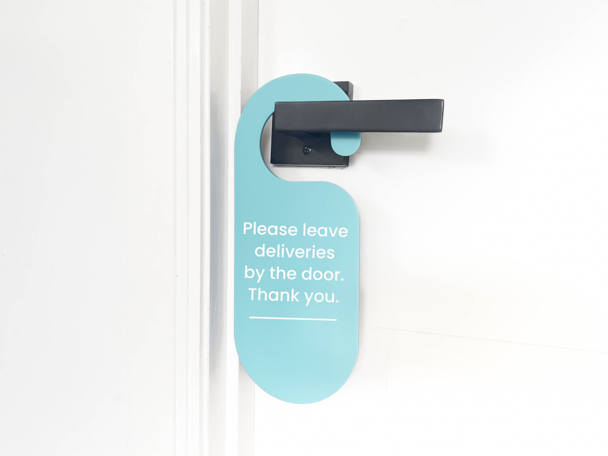 Light teal coloured door hanger that reads 'Please leave deliveries by the door. Thank you."