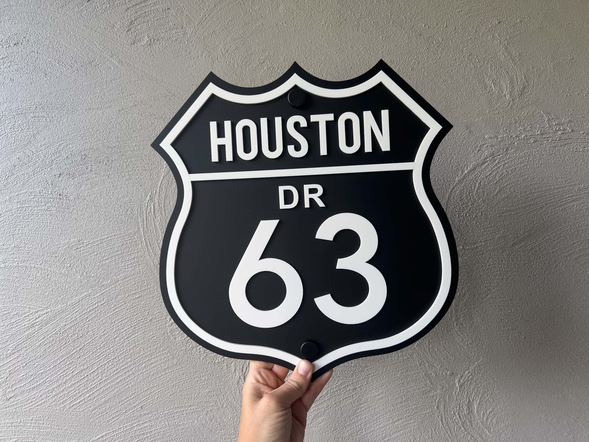 Hand holding a black and white sign with 'HOUSTON DR 63' text against a gray background | Coji Designs