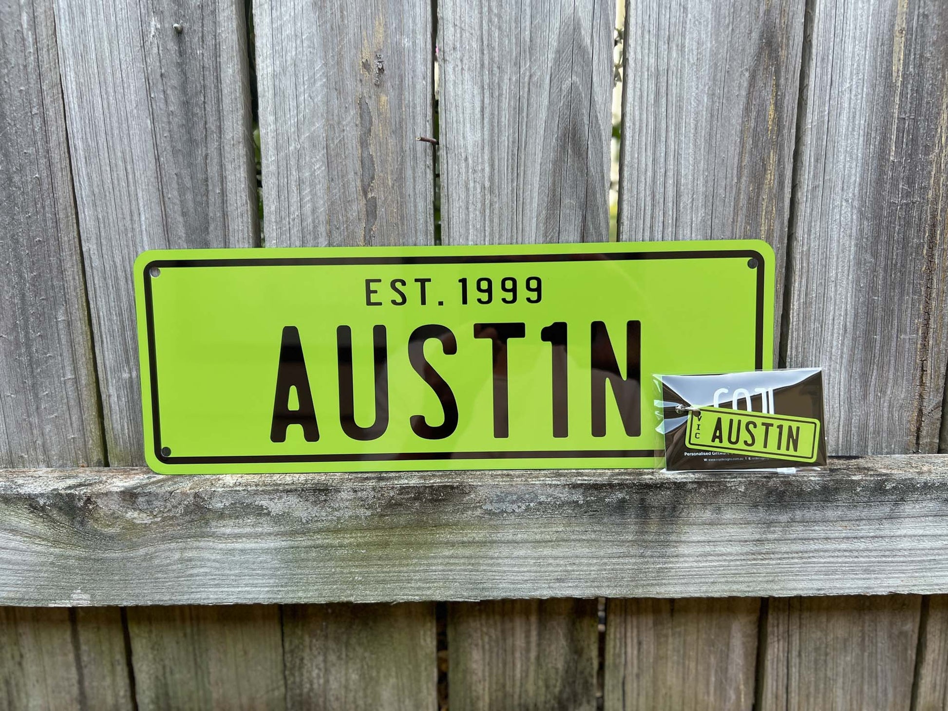 Green sign with 'EST. 1999 AUSTIN' text on a wooden surface