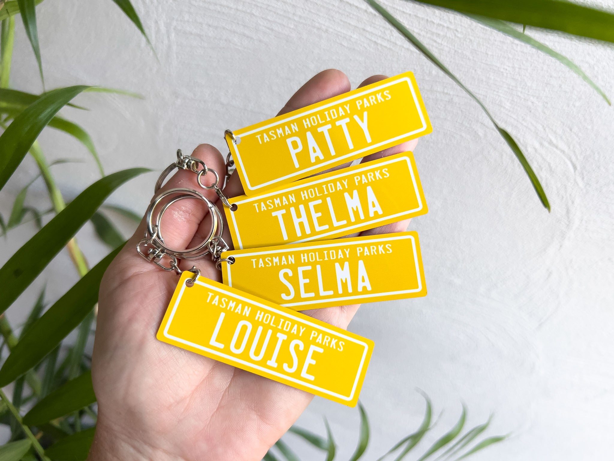 Custom printed aluminium keychains for a holiday parks with fun names in sunshine yellow and white.