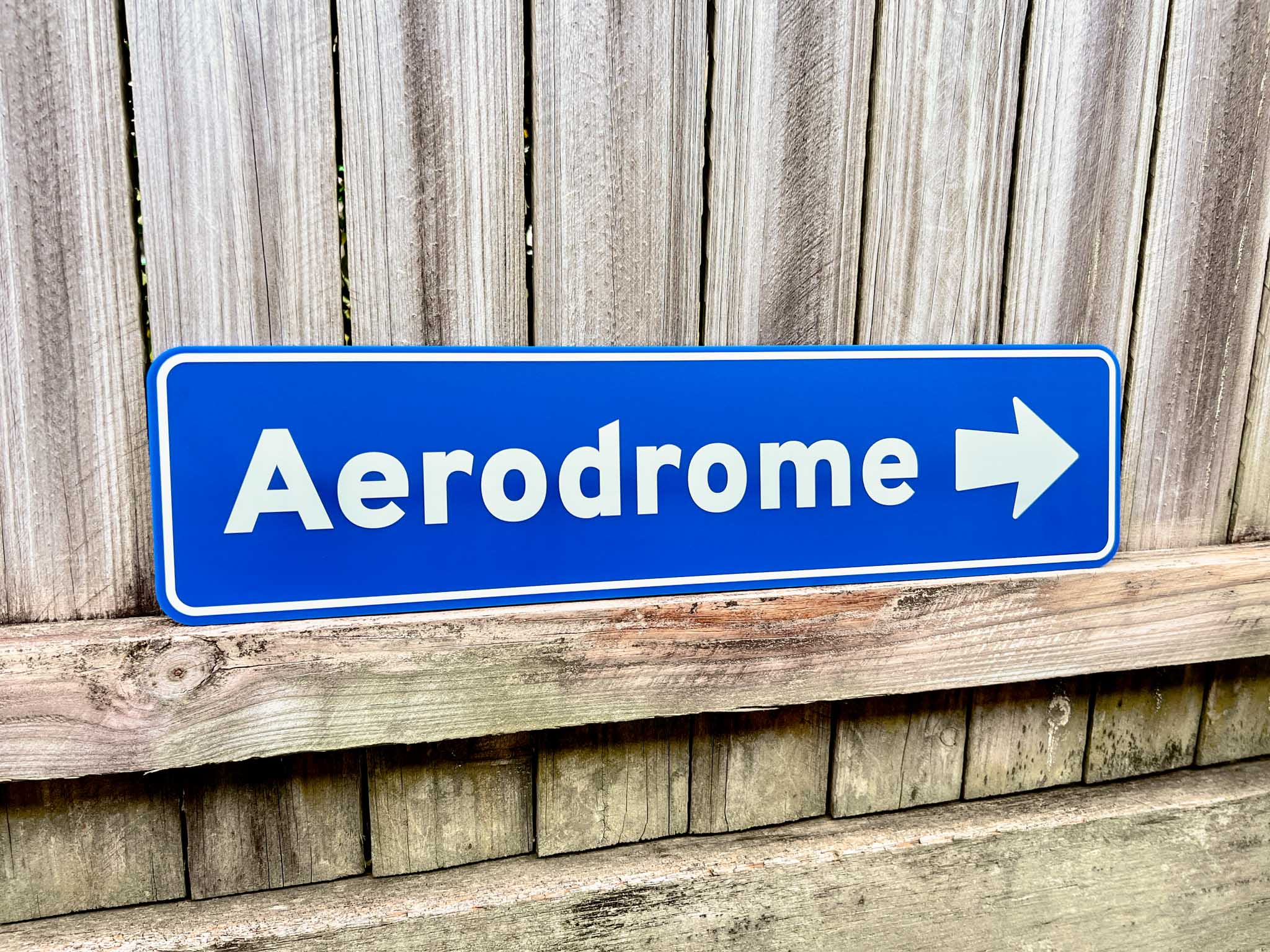 Fun novelty street signs with custom text that reads 'Aerodrome' in a coastal blue colour pointing to the right.