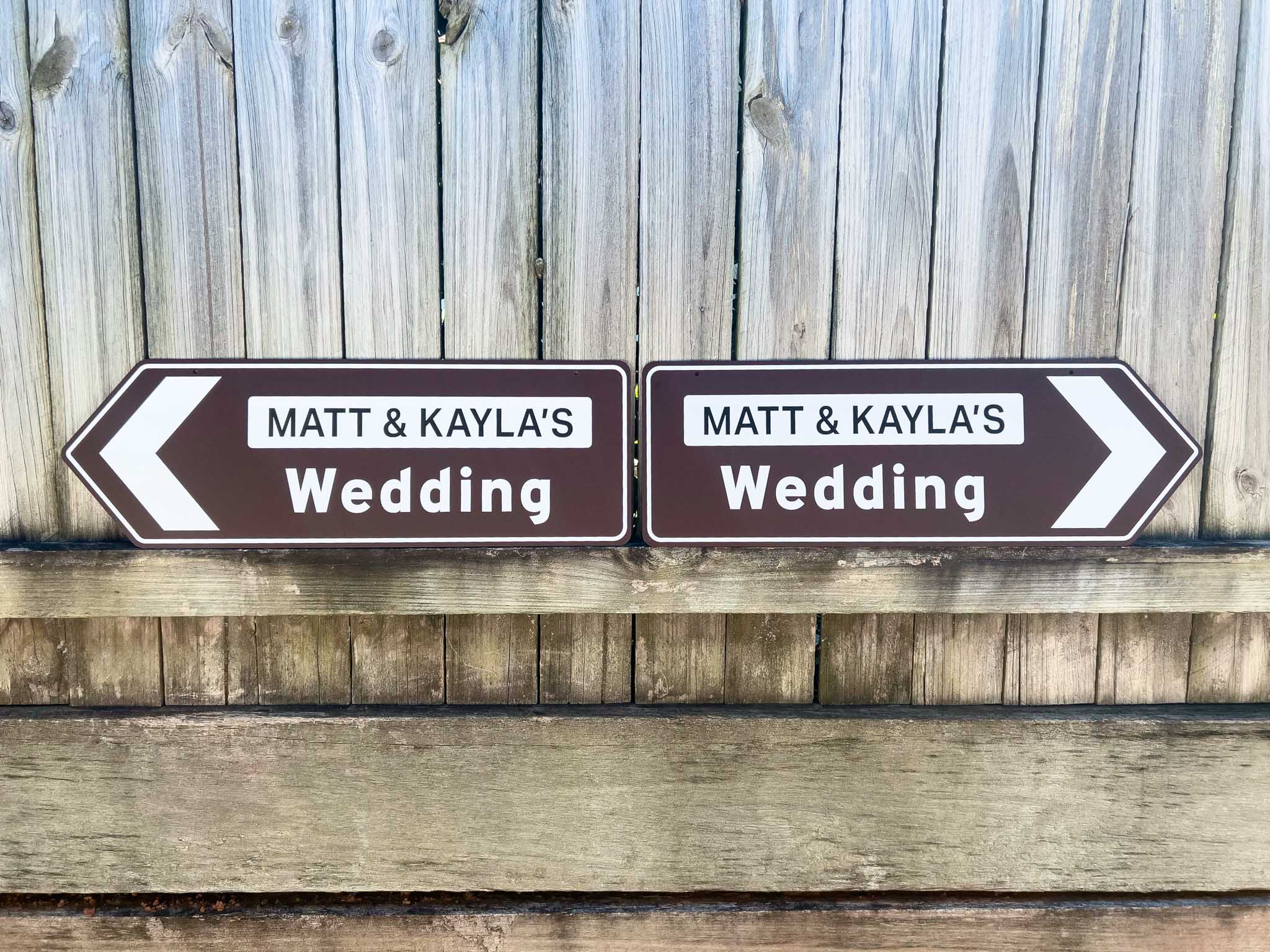 Two wedding direction signs for Matt & Kayla against a wooden background