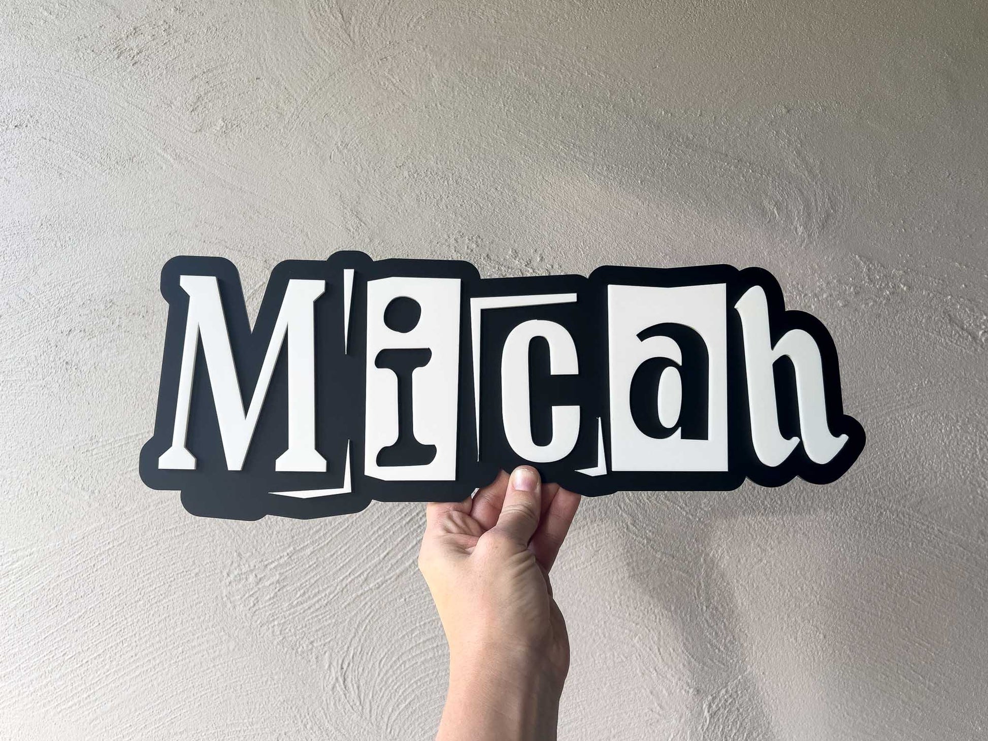 Urban edge style 3D layered acrylic wall name plaque for children's room that reads 'Micah' in black and white.