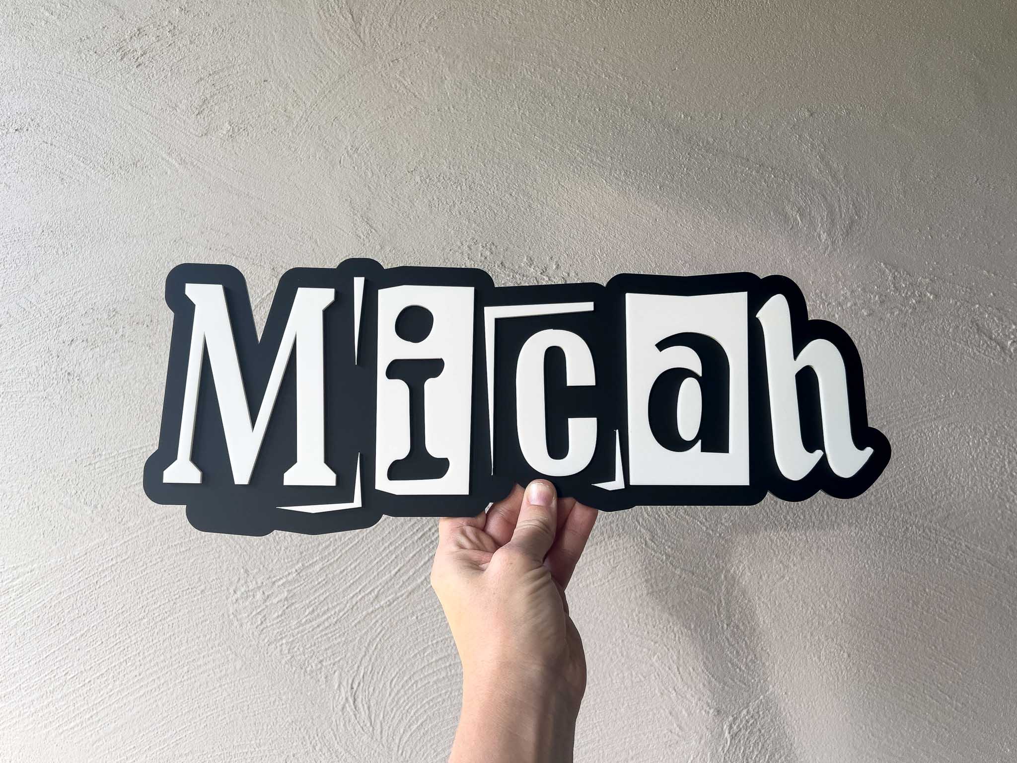 Urban edge style 3D layered acrylic wall name plaque for children's room that reads 'Micah' in black and white.