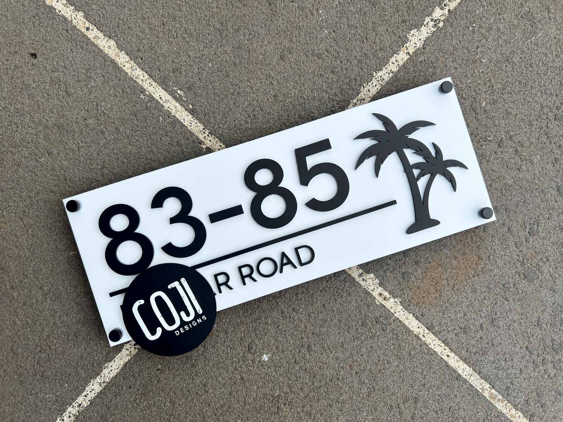 Custom handmade white and black tropical palm tree address sign with the numbers '83-85'.