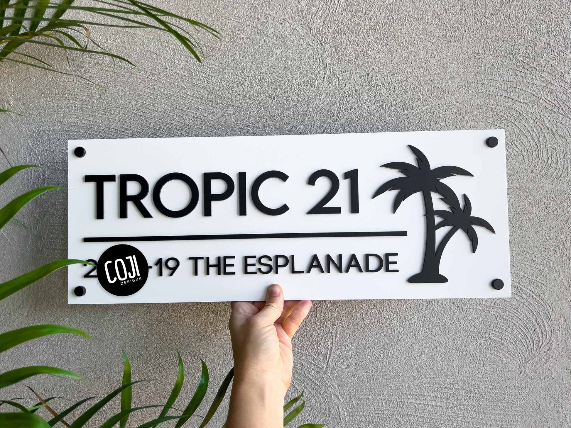 Rectangle white and black tropical palm tree house sign that reads 'TROPIC 21'.