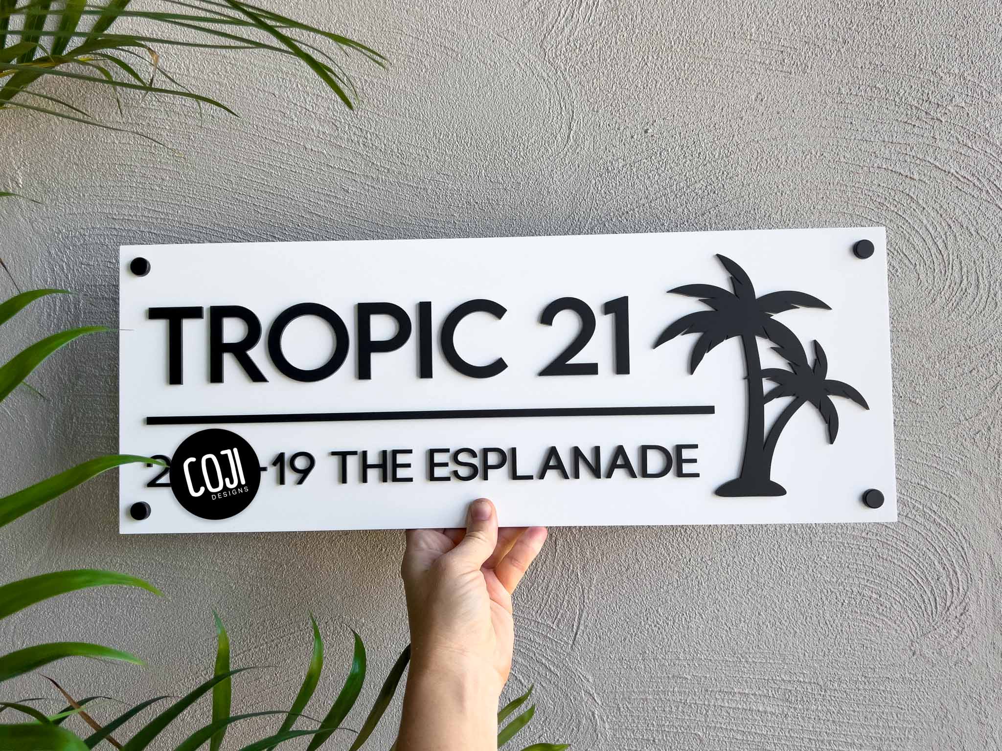 Rectangle white and black tropical palm tree house sign that reads 'TROPIC 21'.