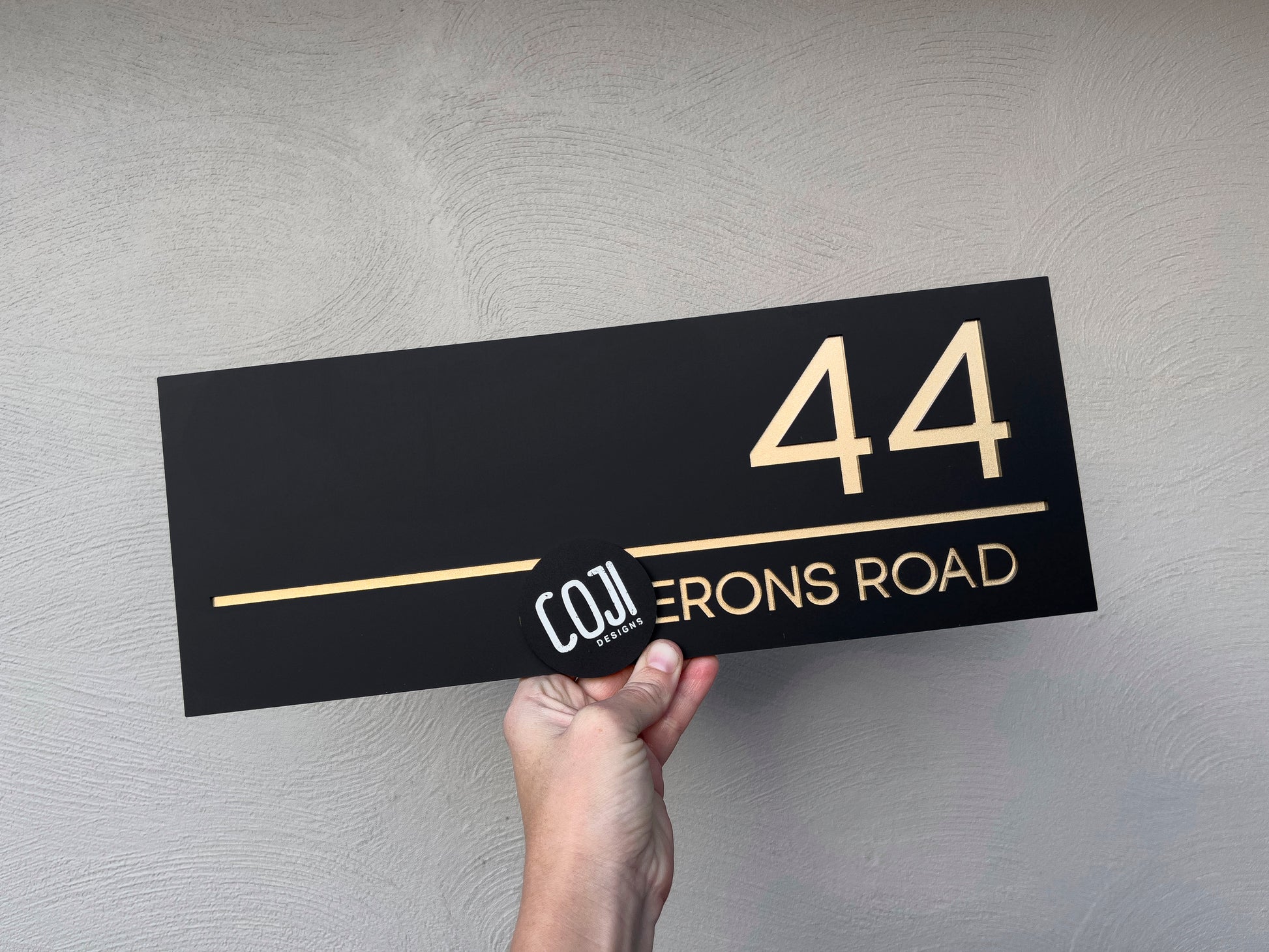 Black and metallic gold custom made acrylic house address sign with the number '44'.