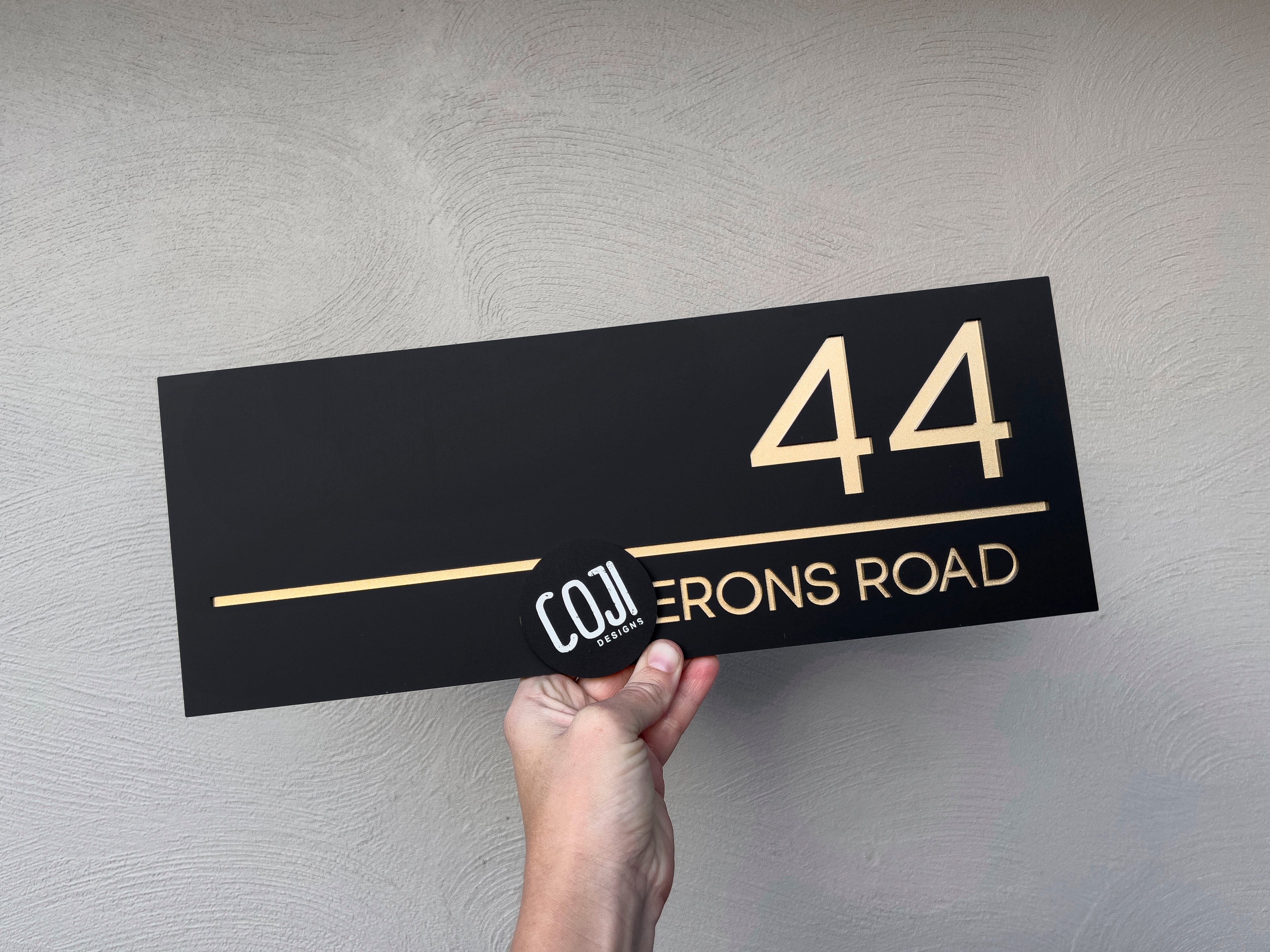 Black and metallic gold custom made acrylic house address sign with the number '44'.