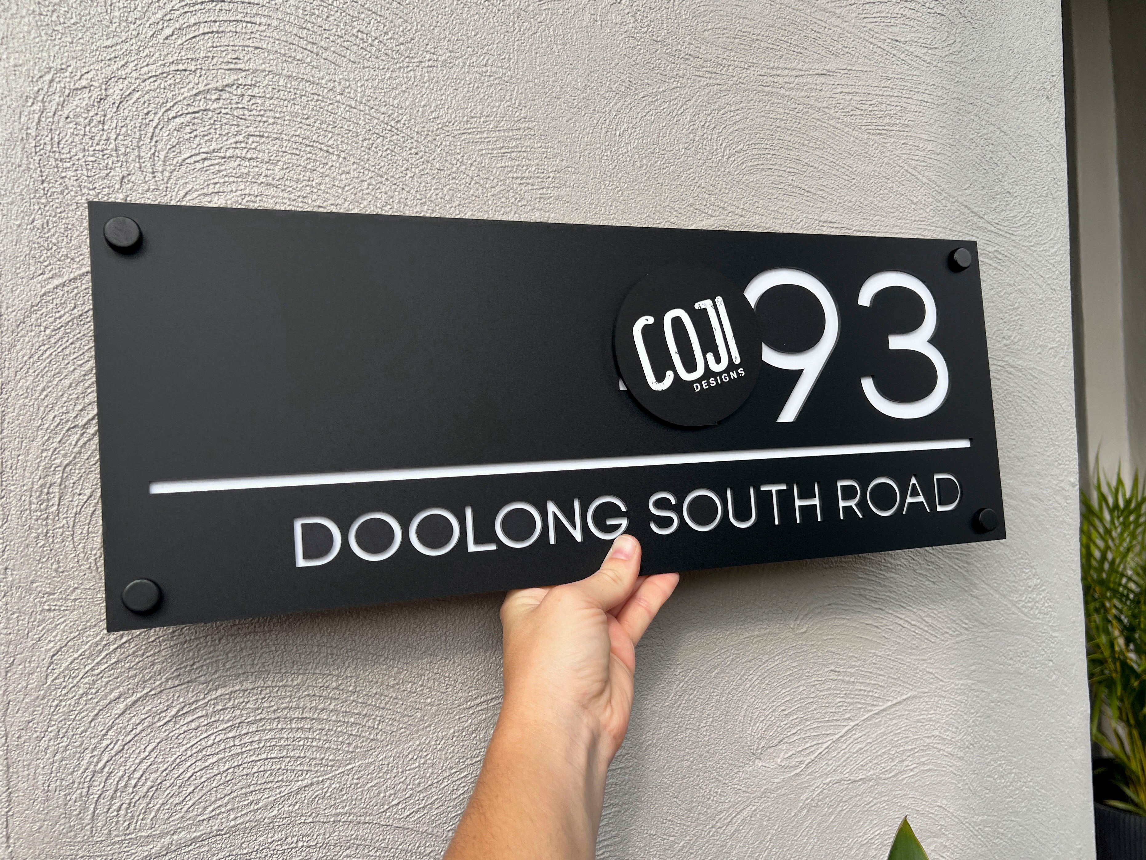 Custom made double layered acrylic house sign in black and white with black mounts.