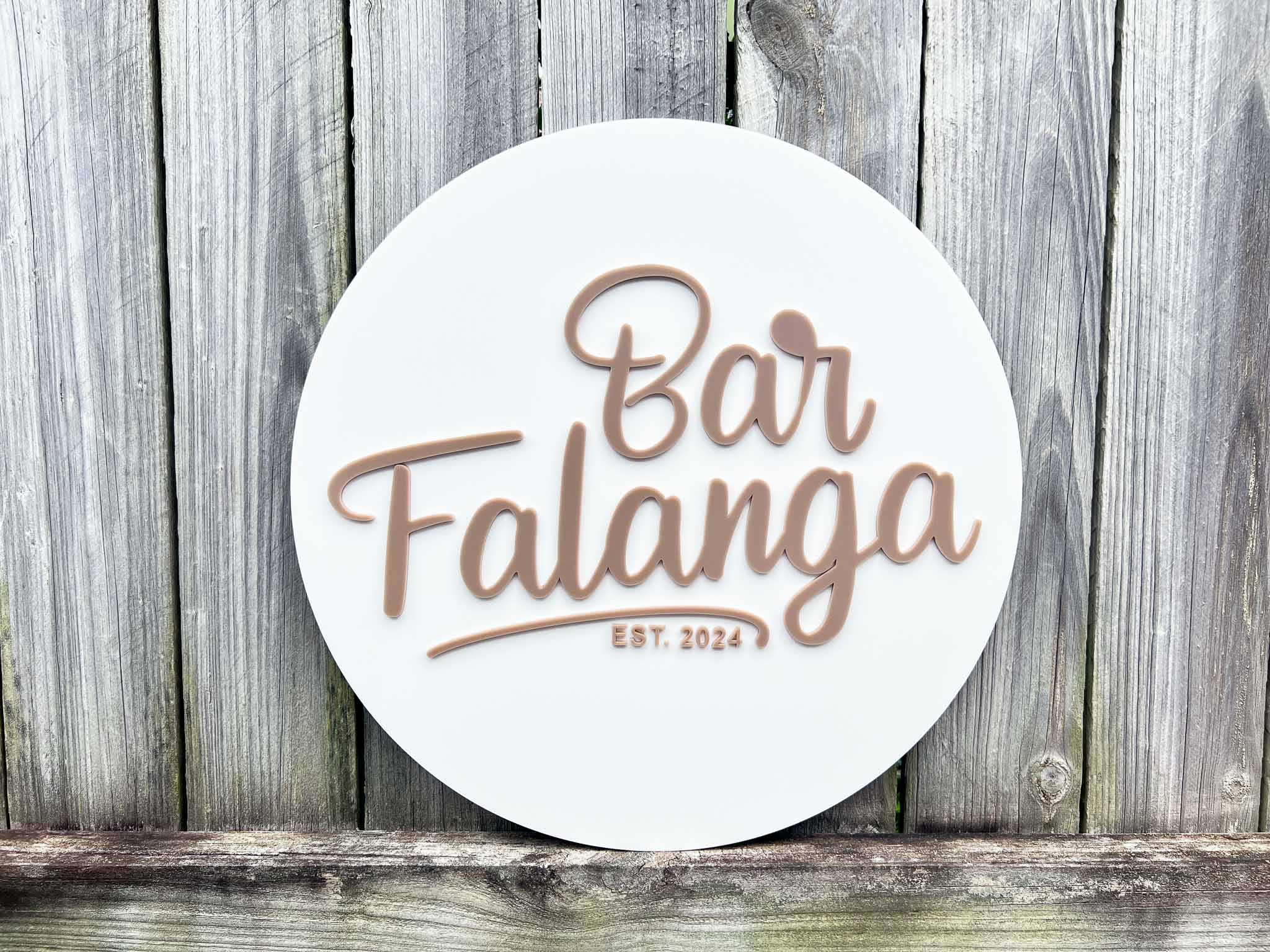 Round sign with 'Bar Falanga' text on a wooden background