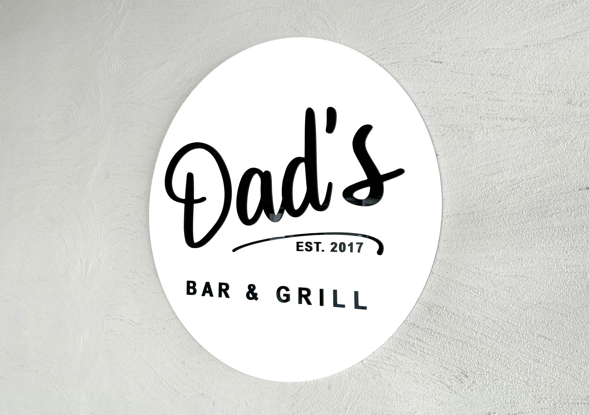 Custom round 3D acrylic sign that says 'Dads Bar & Grill' in white and black.
