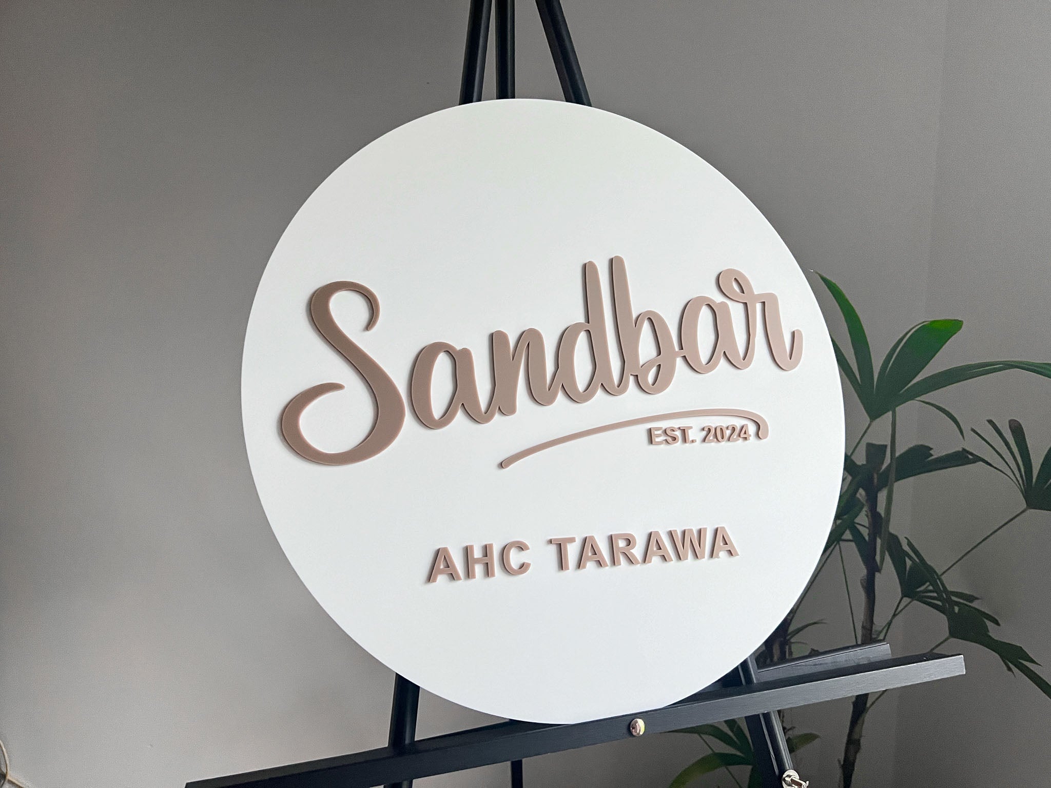 Round personalised sign with 'Sandbar' and 'AHC Tarawa' text on a stand against a neutral background