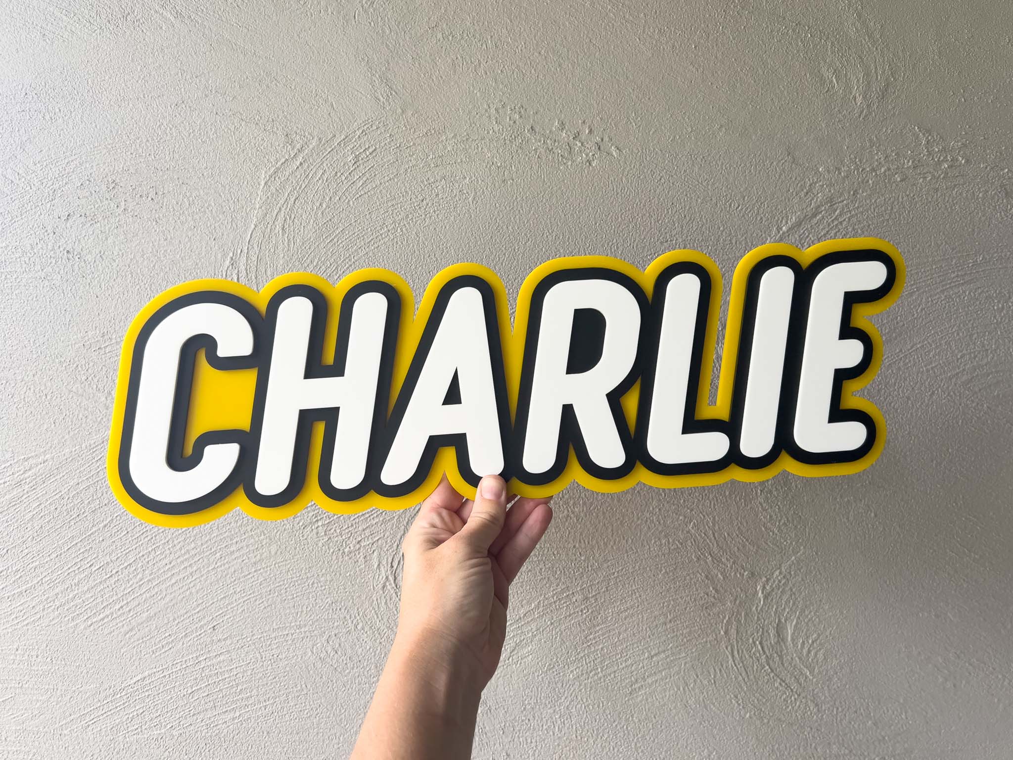 Custom made three layer acrylic name plaque with the name 'Charlie' made in yellow, black and white.