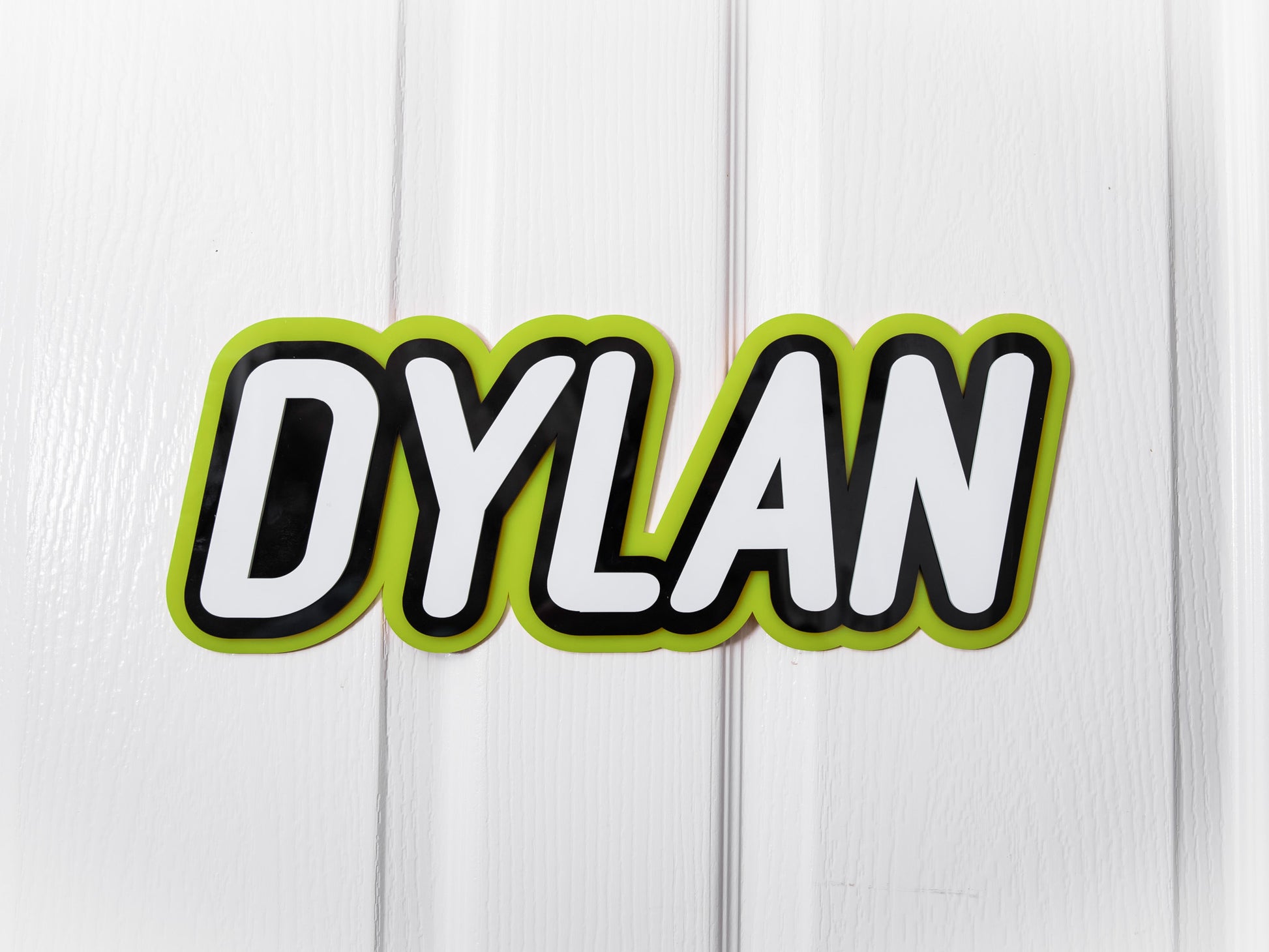 Personalised multi-layed acrylic name plaque with the name 'Dylan' in lime green, black and white.