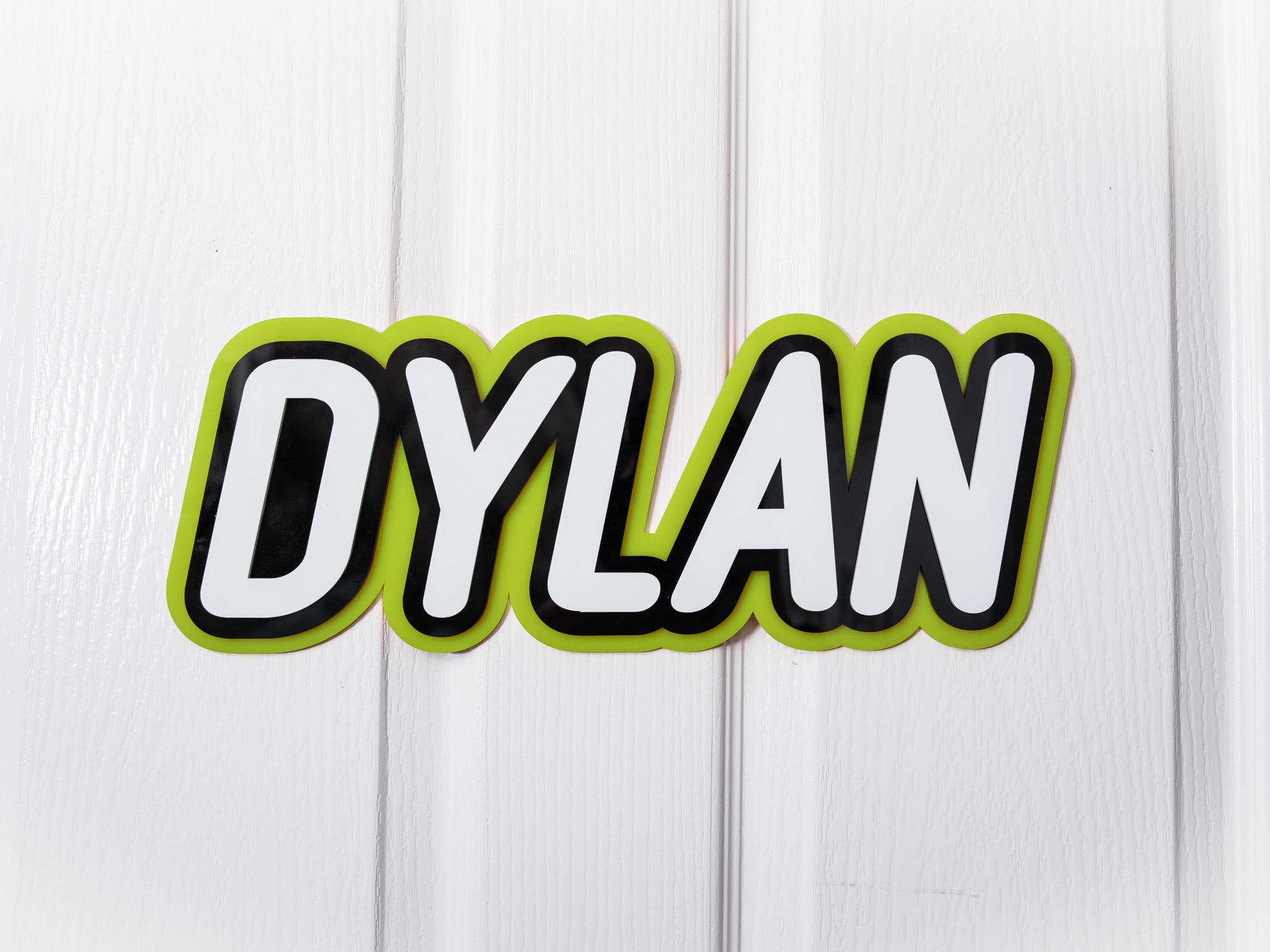 Personalised multi-layed acrylic name plaque with the name 'Dylan' in lime green, black and white.