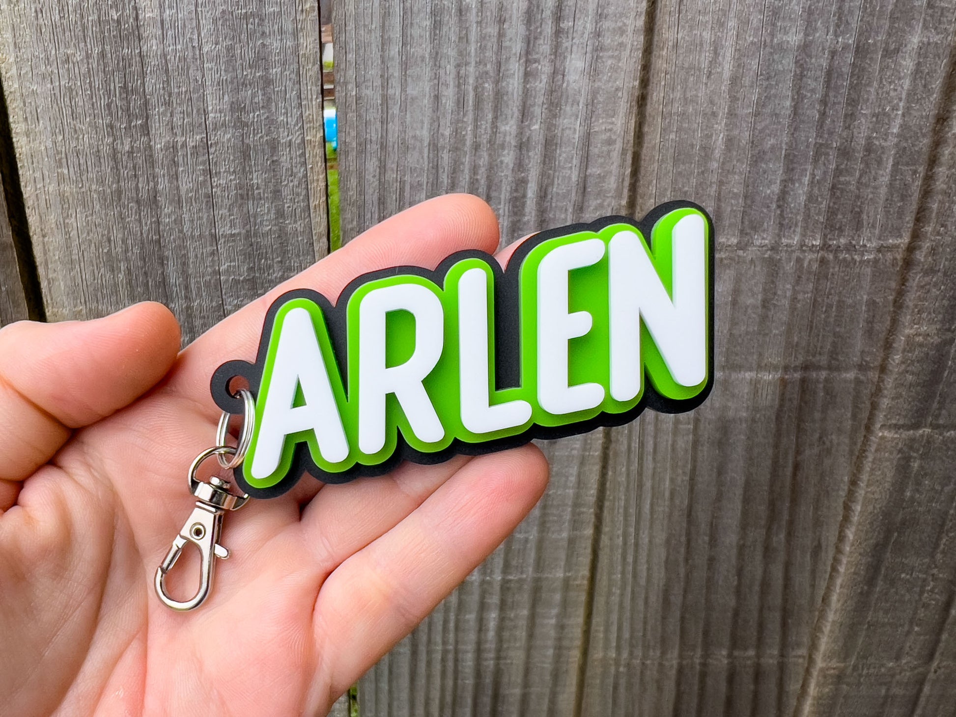 A retro inspired bold font 3D acrylic keychain in black, lime green and white with the name "ARLEN'.