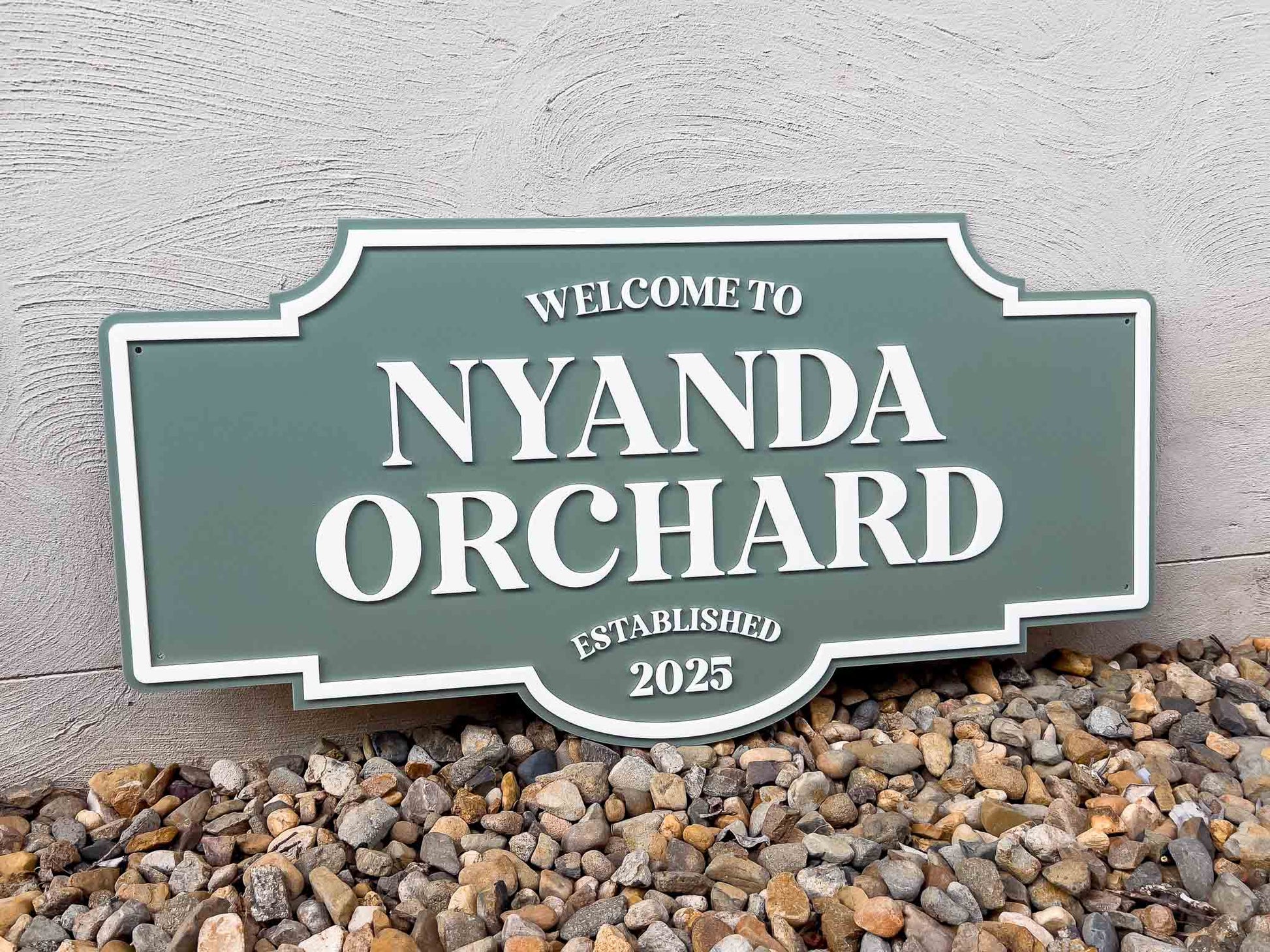 Personalised outdoor retro style sign with Welcome to Nyanda Orchard on a textured wall background.