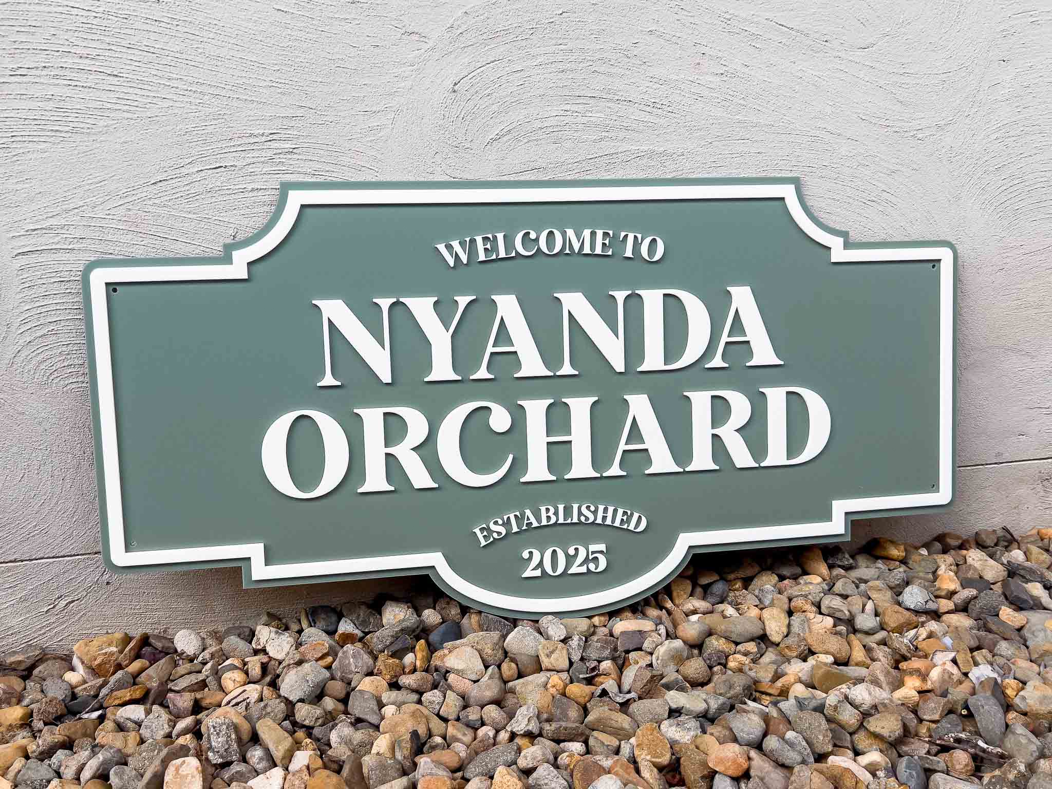Personalised outdoor retro style sign with Welcome to Nyanda Orchard on a textured wall background.