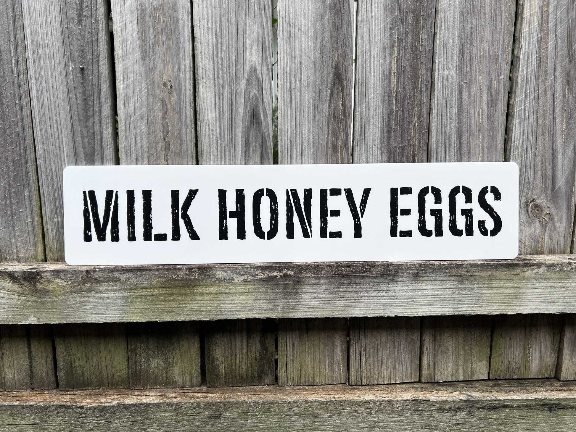 Personalised custom text wall art with the custom text 'MILK HONEY EGGS' printed in a distressed stencil typography.