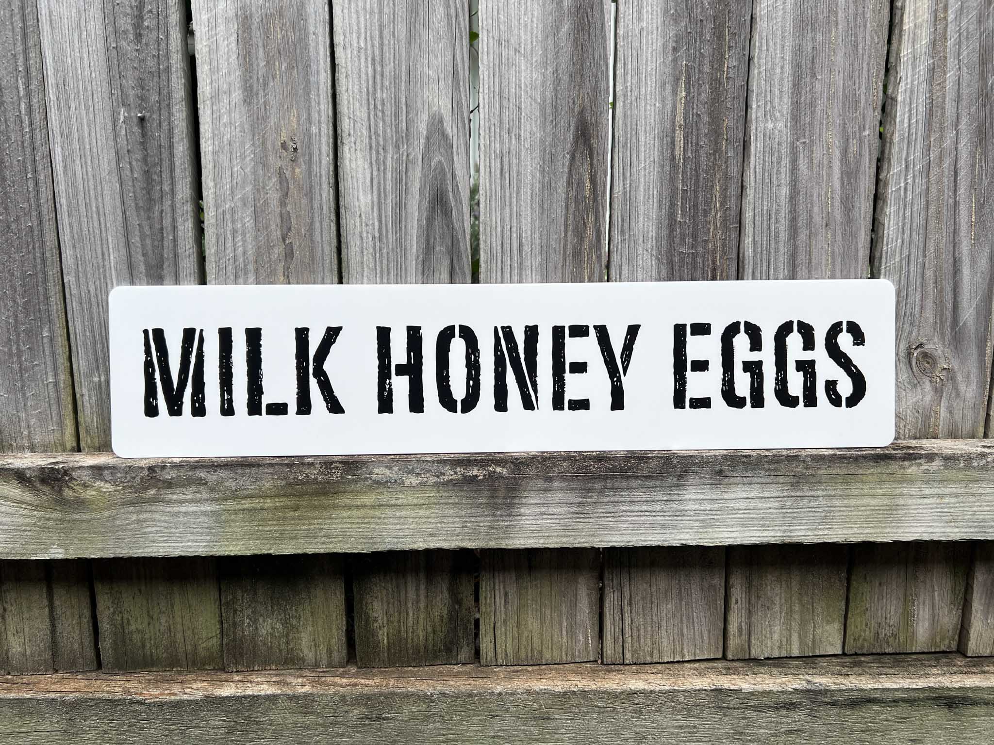 Personalised custom text wall art with the custom text 'MILK HONEY EGGS' printed in a distressed stencil typography.