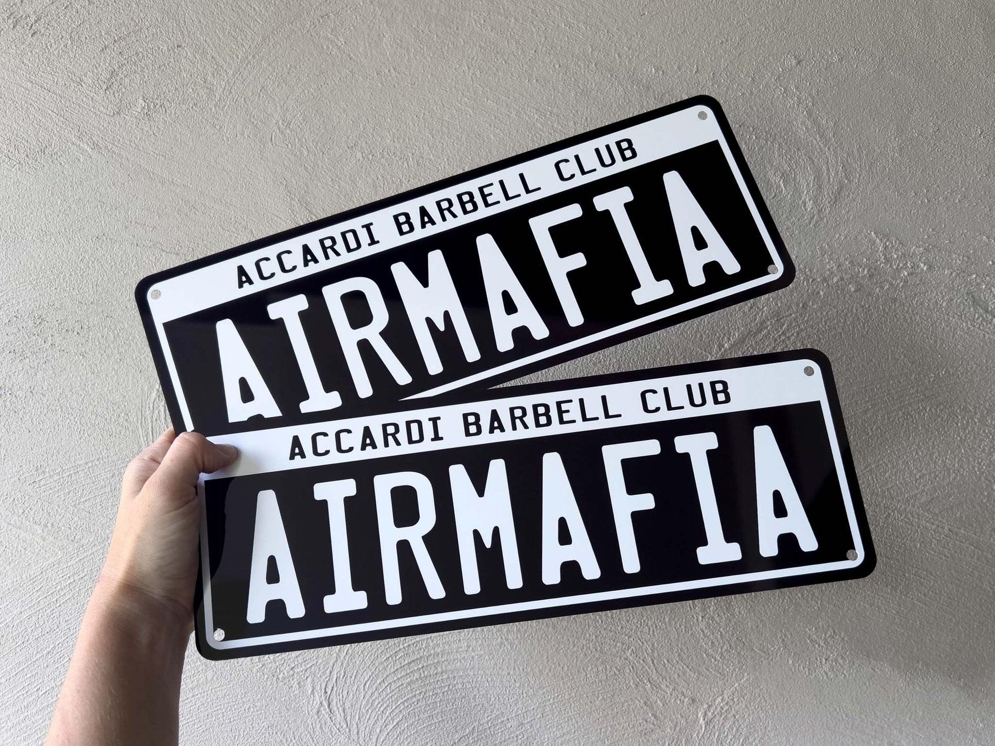 Two 'AIRMAFIA' signs held against a light gray background