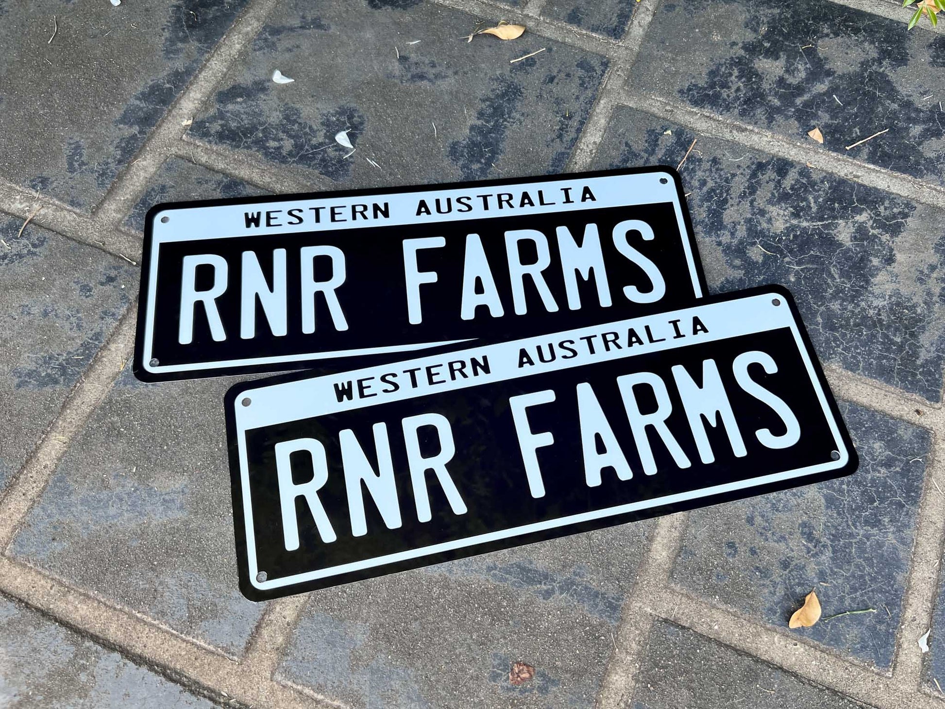 Two RNR Farms number plates style business plates on a concrete pavement
