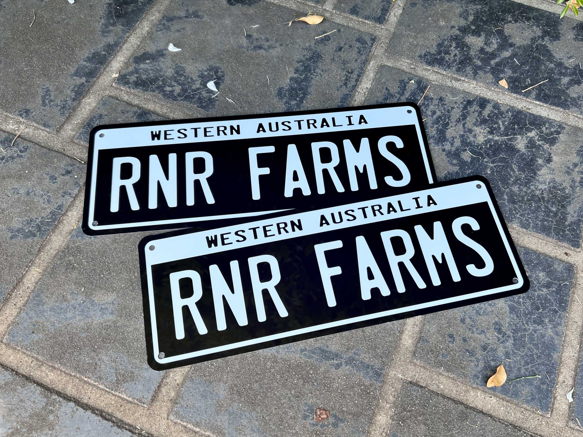 Two RNR Farms number plates style business plates on a concrete pavement