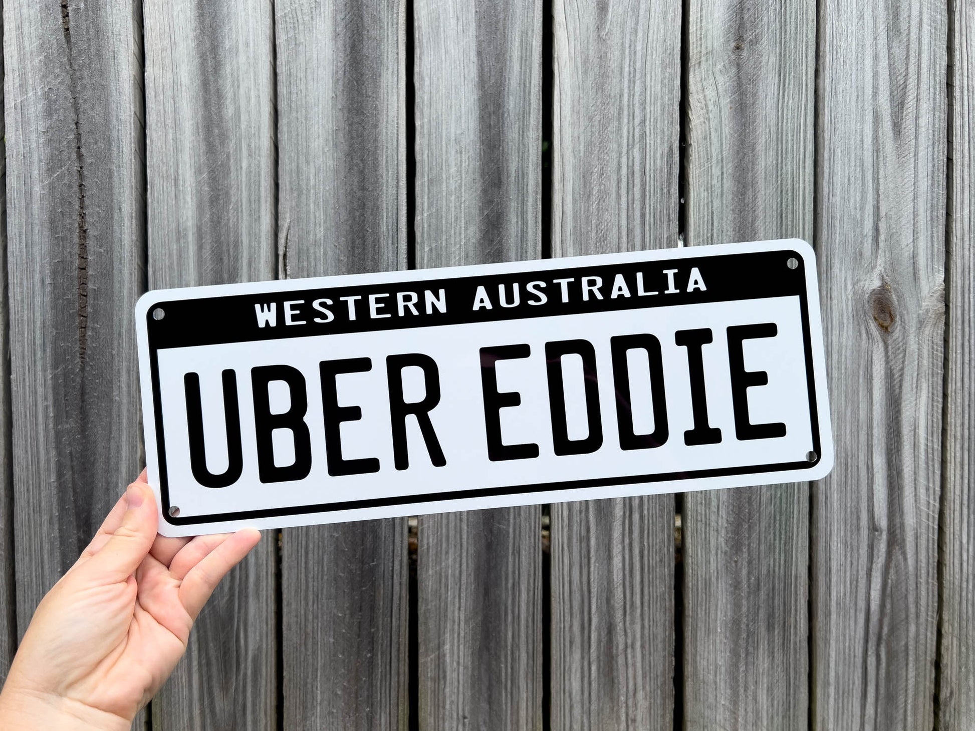 Person holding a plate with 'Uber Eddie' text against a wooden background