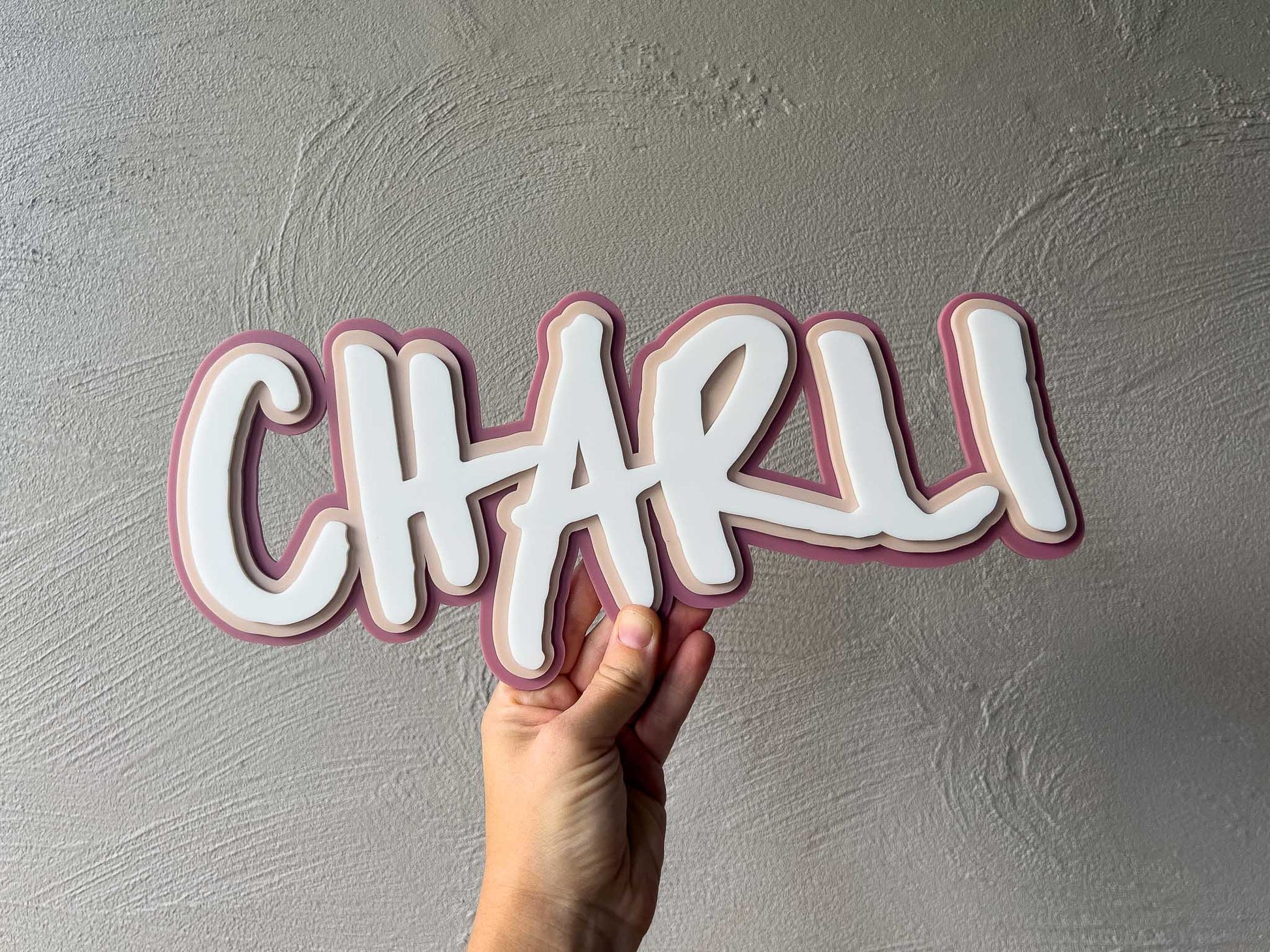 Skater style personalised name plaque that says 'Charli' in dusty rose, beige and white.