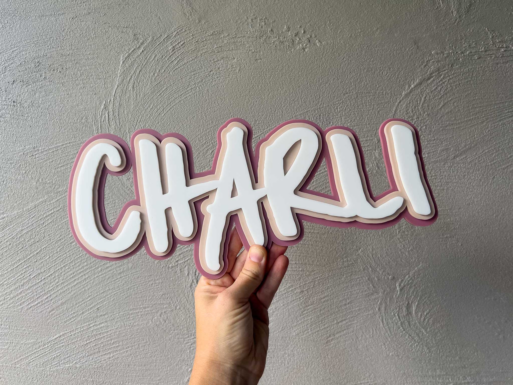 Skater style personalised name plaque that says 'Charli' in dusty rose, beige and white.