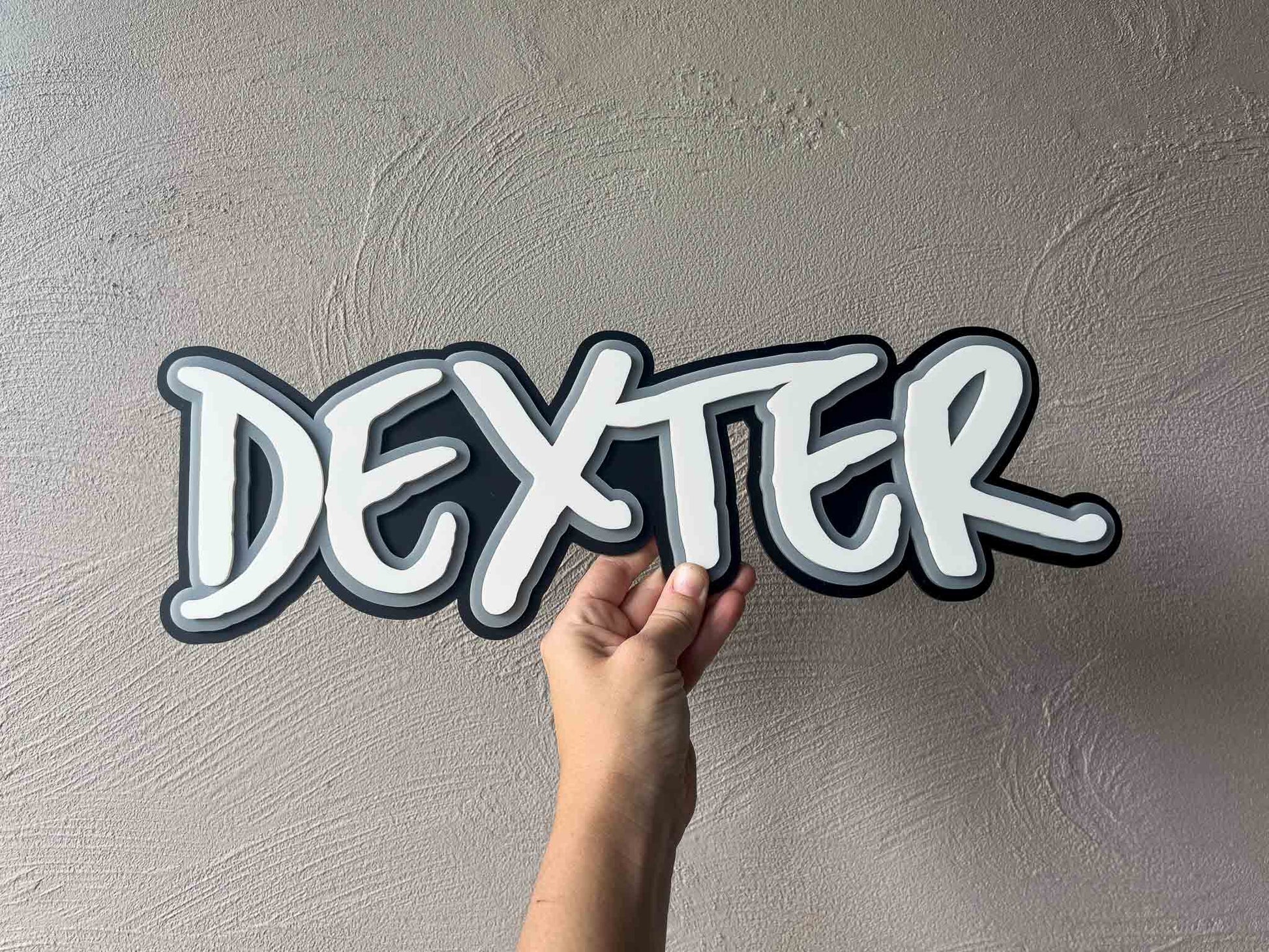 A rad style, graffitti inspired custom acrylic name plaque that reads 'Dexter' in black, white and grey.