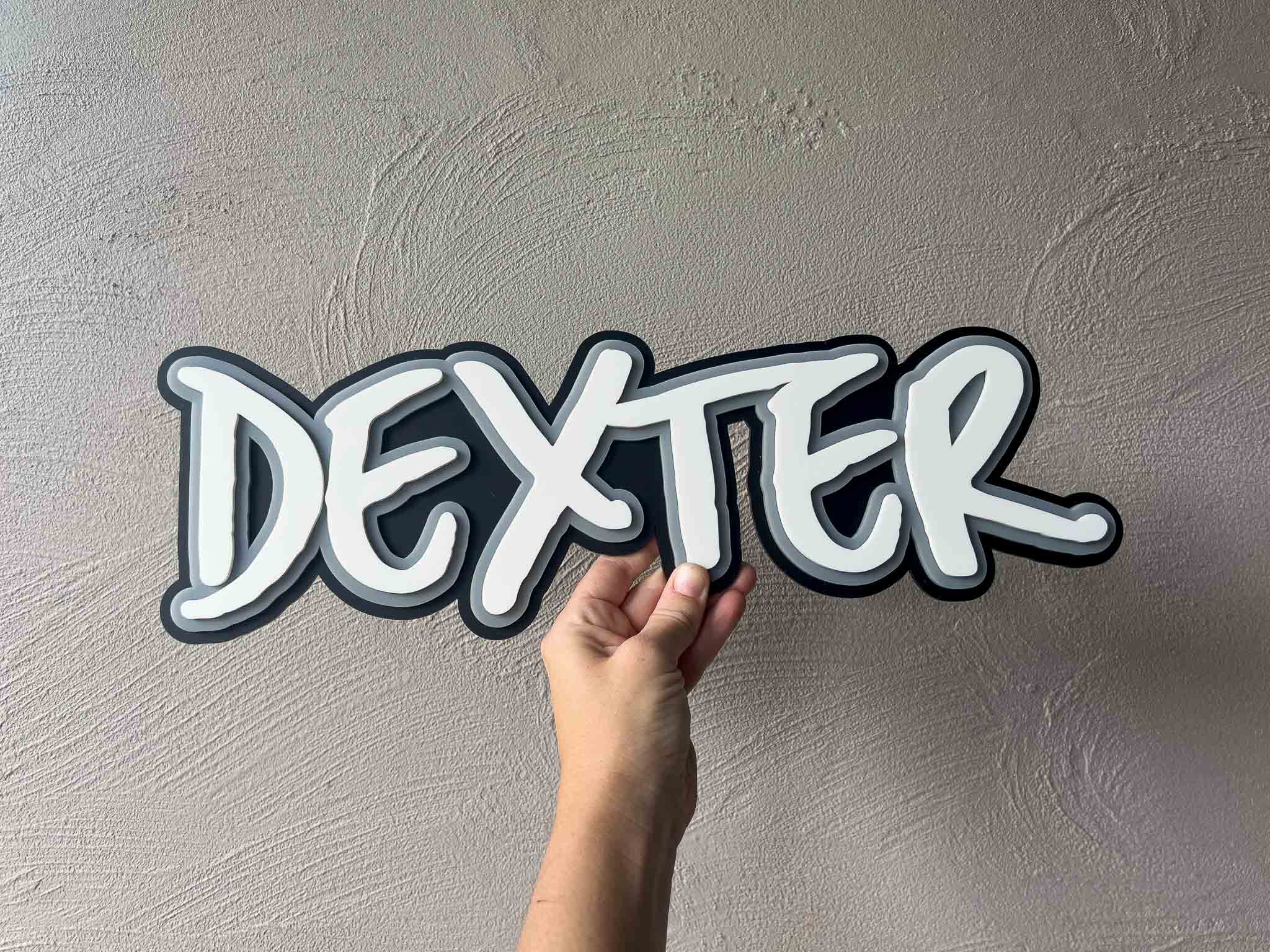 A rad style, graffitti inspired custom acrylic name plaque that reads 'Dexter' in black, white and grey.