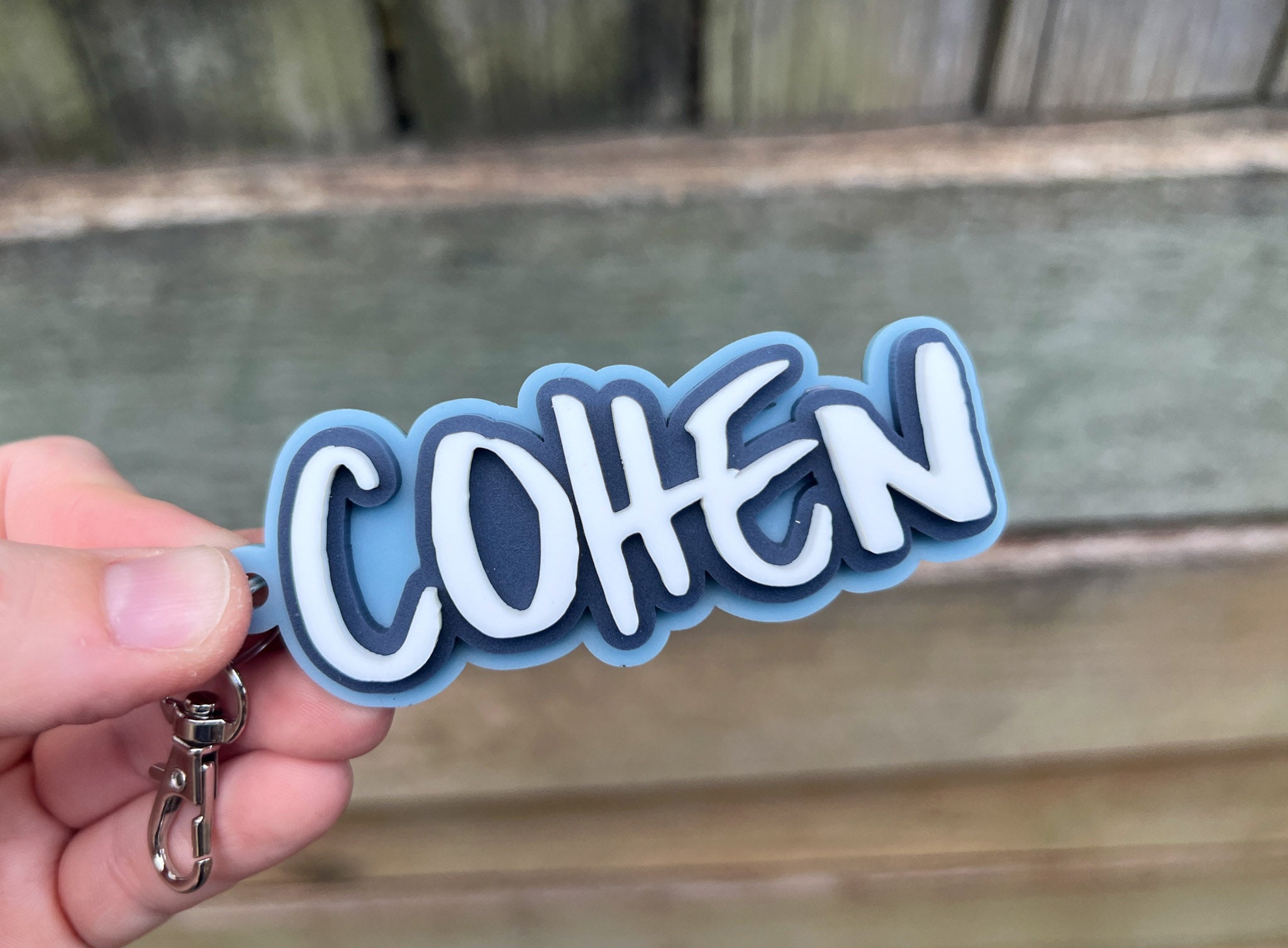 Skate style surf keychain in retro blue and white that says 'Cohen'.