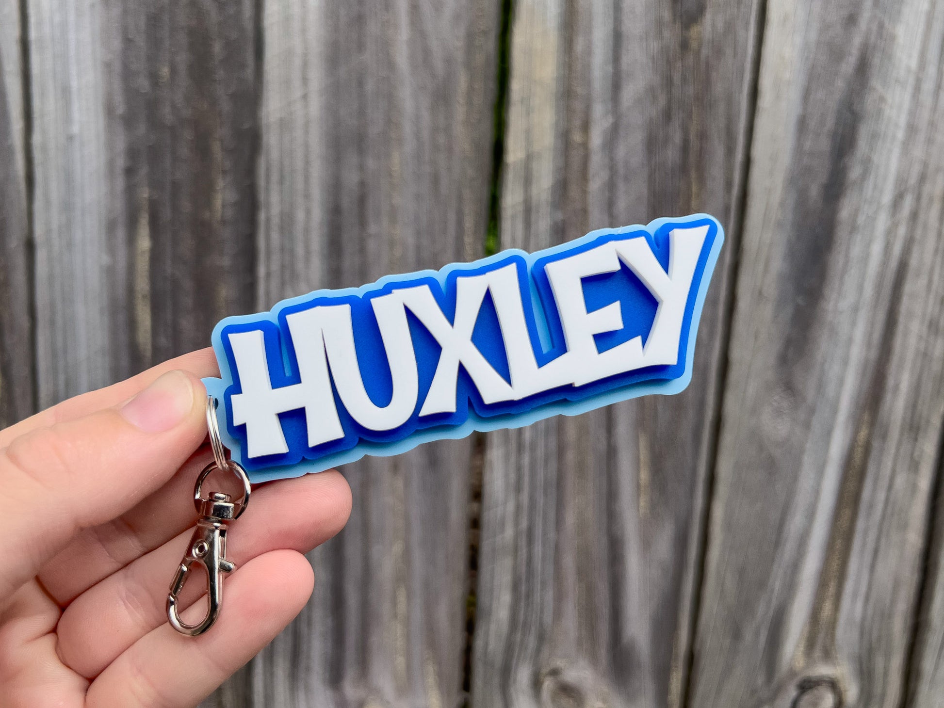Personalised 3D acrylic keychian with the name 'Huxley' in light blue, dark blue and white.