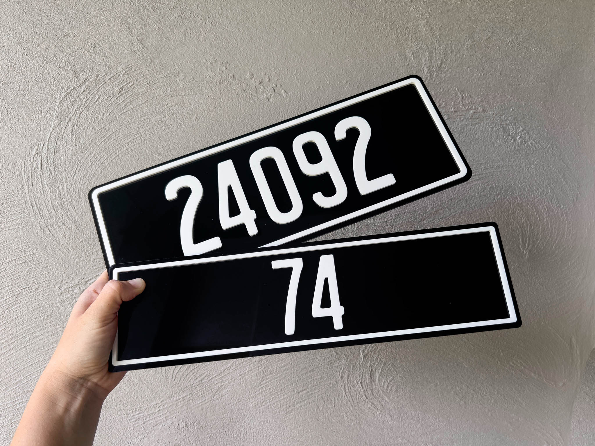 Two black acrylic plates with the numbers '24092' & '74' in white 3D acrylic lettering.