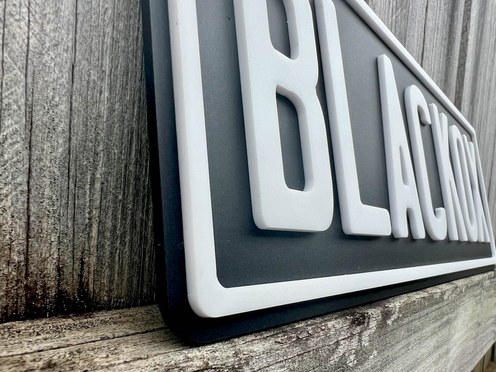 A close up side view of a matt black and white acrylic 3D plate.