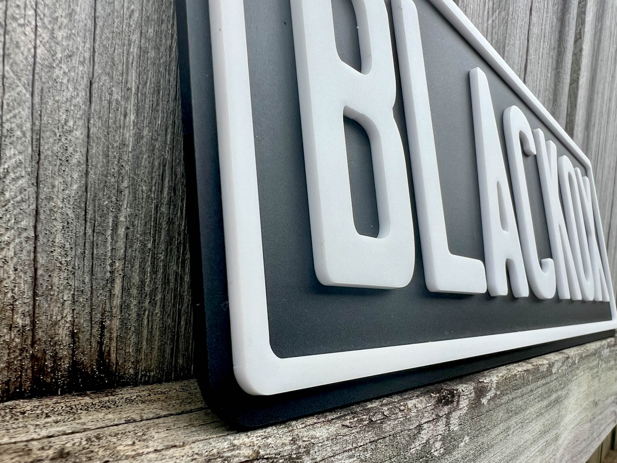 A close up side view of a matt black and white acrylic 3D plate.