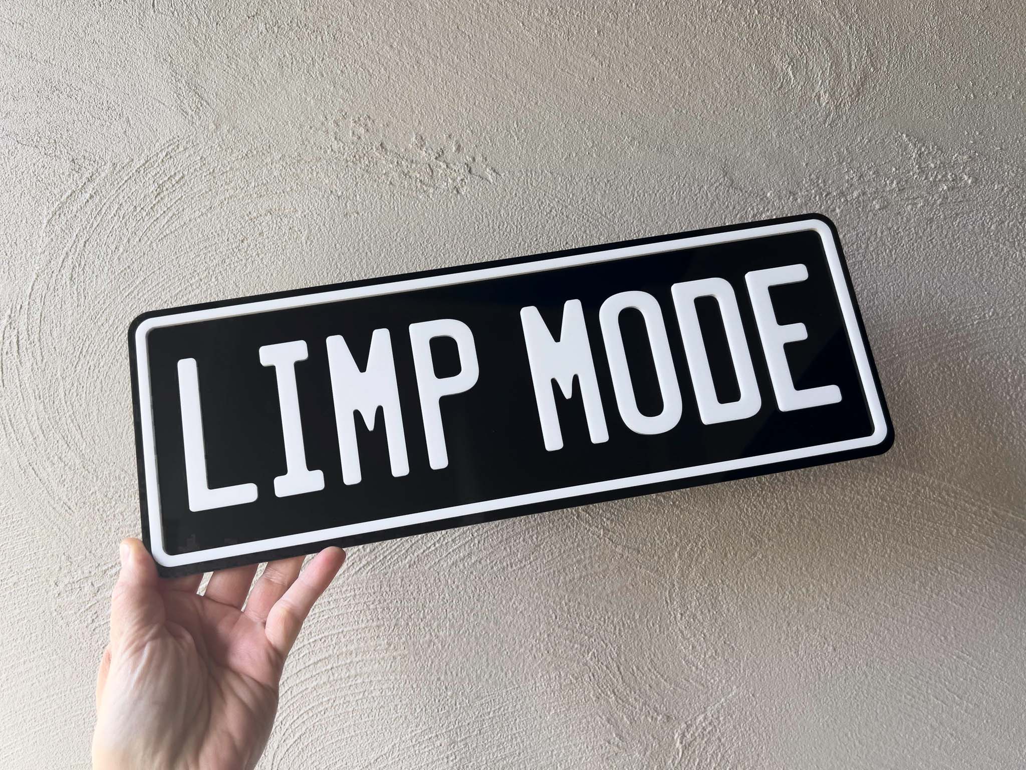 A black and white acrylic plate that reads 'LIMP MODE' on a black plate with white lettering.