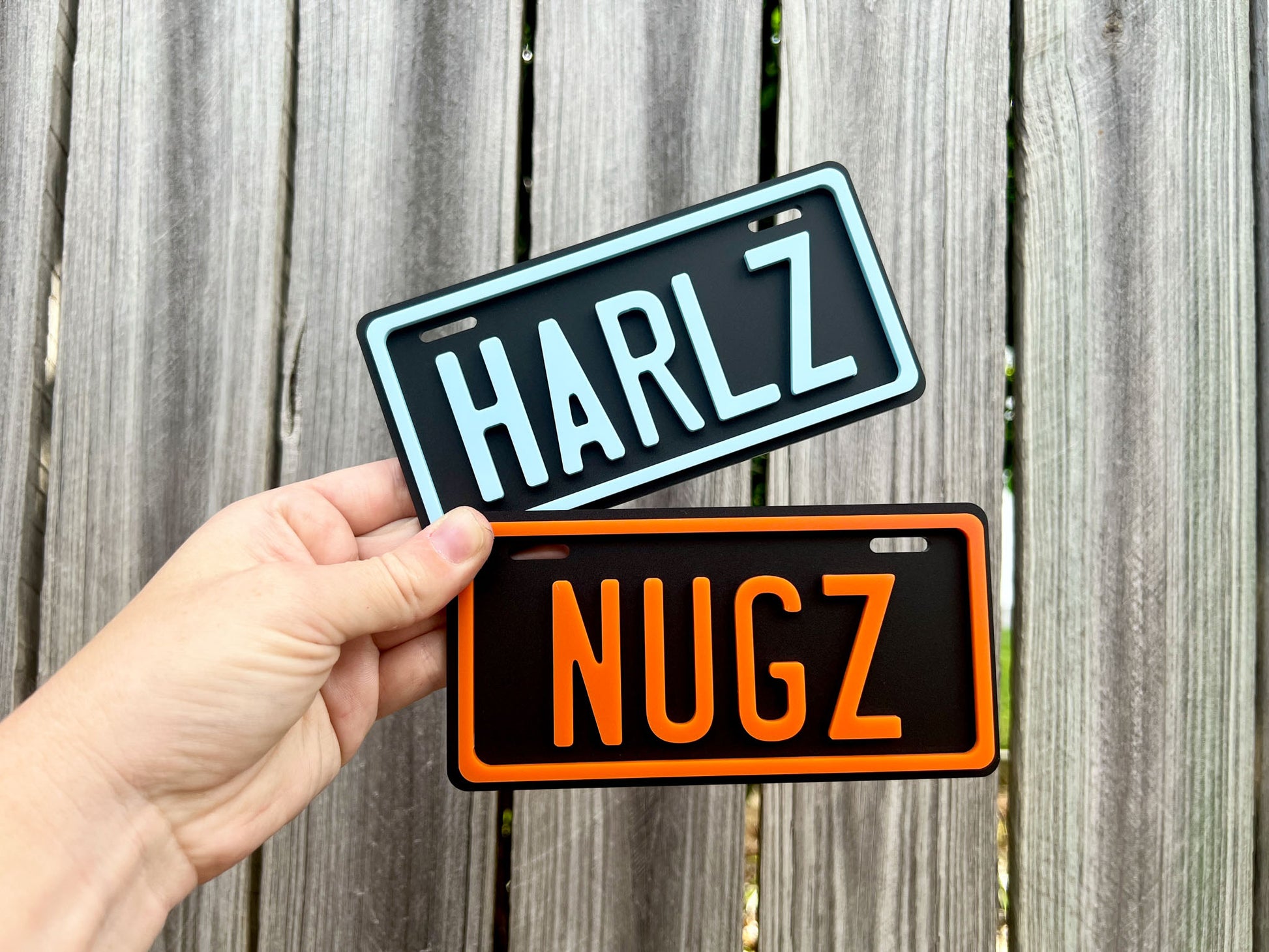 Two license plate-style signs with 'HARLZ' and 'NUGZ' made from black, white and orange acrylic.