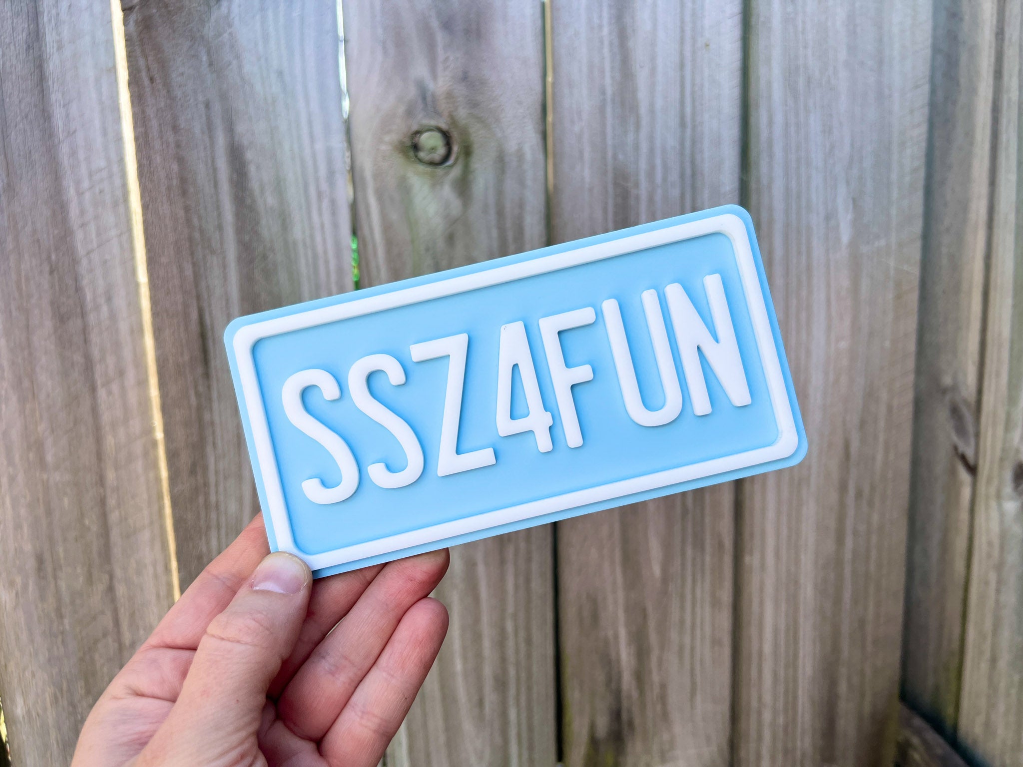A personalised mini number plate in blue and white acrylic that reads 'SSZ4FUN'.