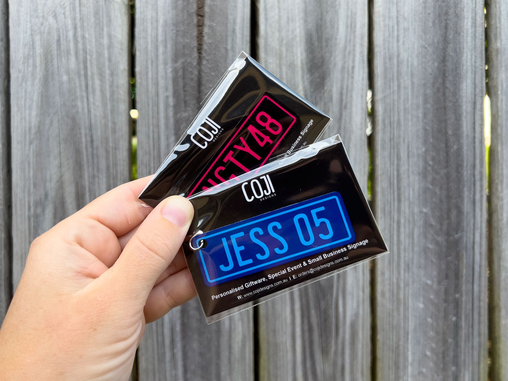 Two custom printed aluminium number plate style keychains in pink and blue.
