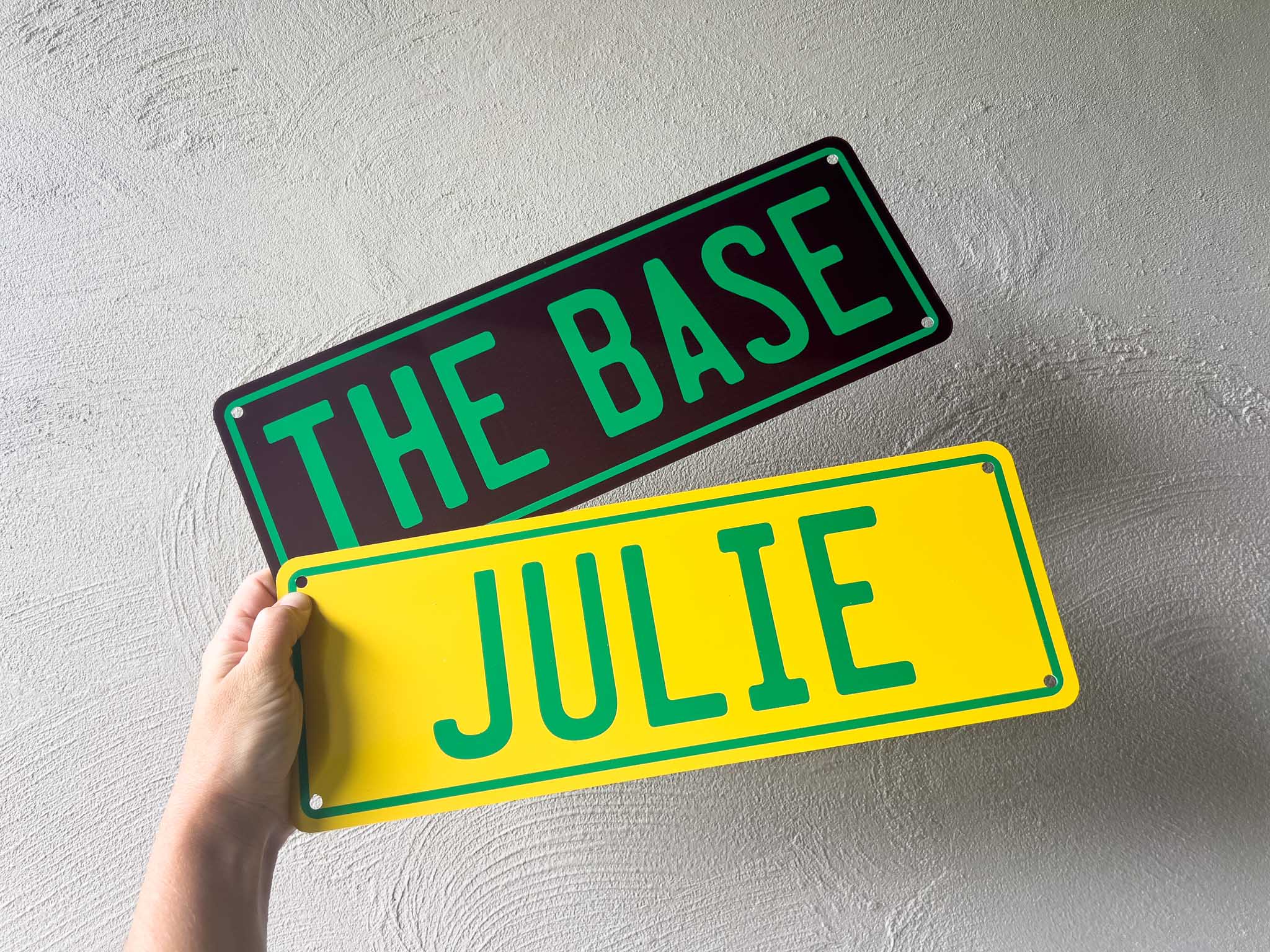 Two custom printed number plate style signs in brown, green and yellow.