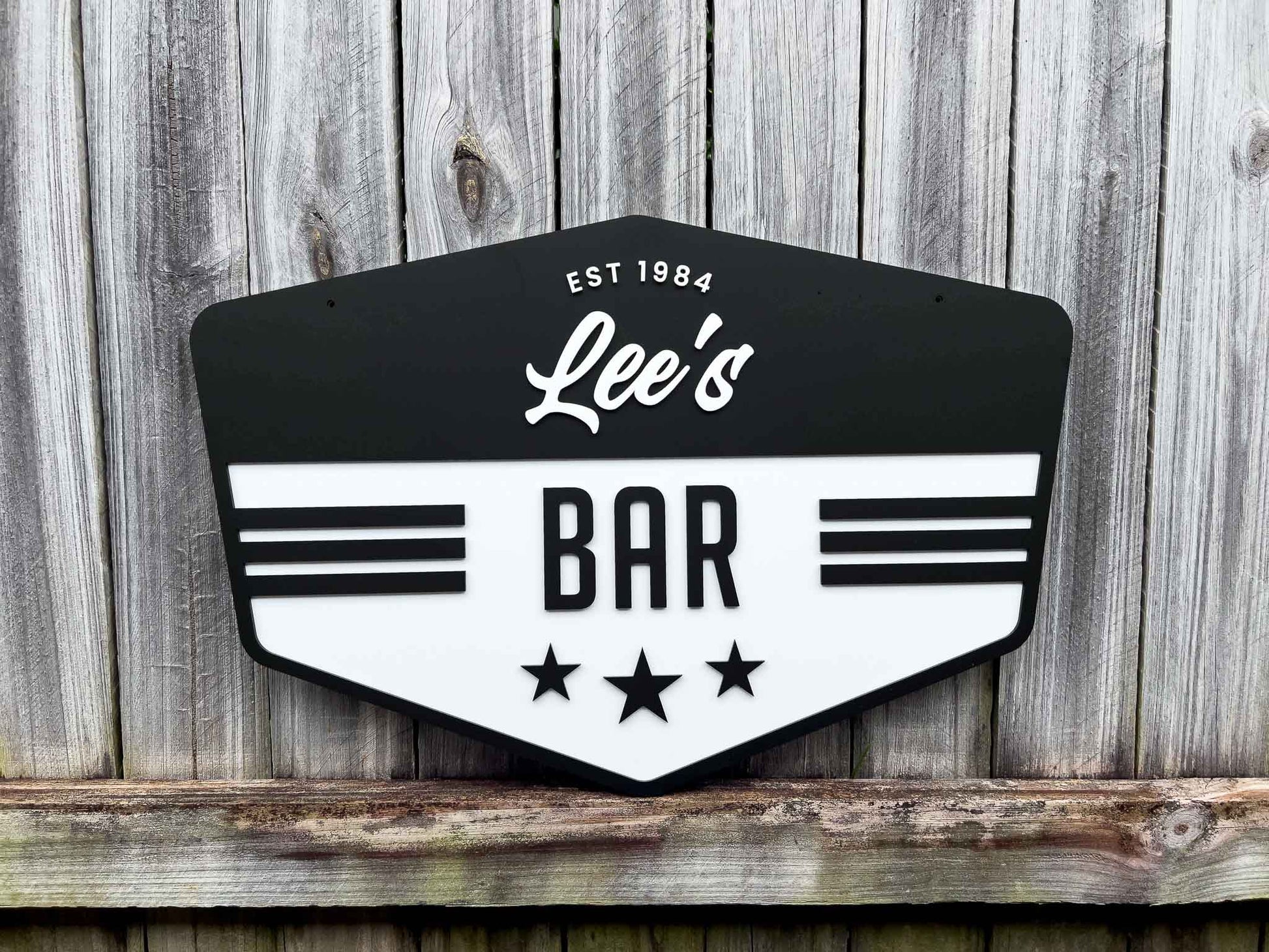Classic custom-made vintage badge sign for 'Lee's Bar' with a black and white design on a wooden background