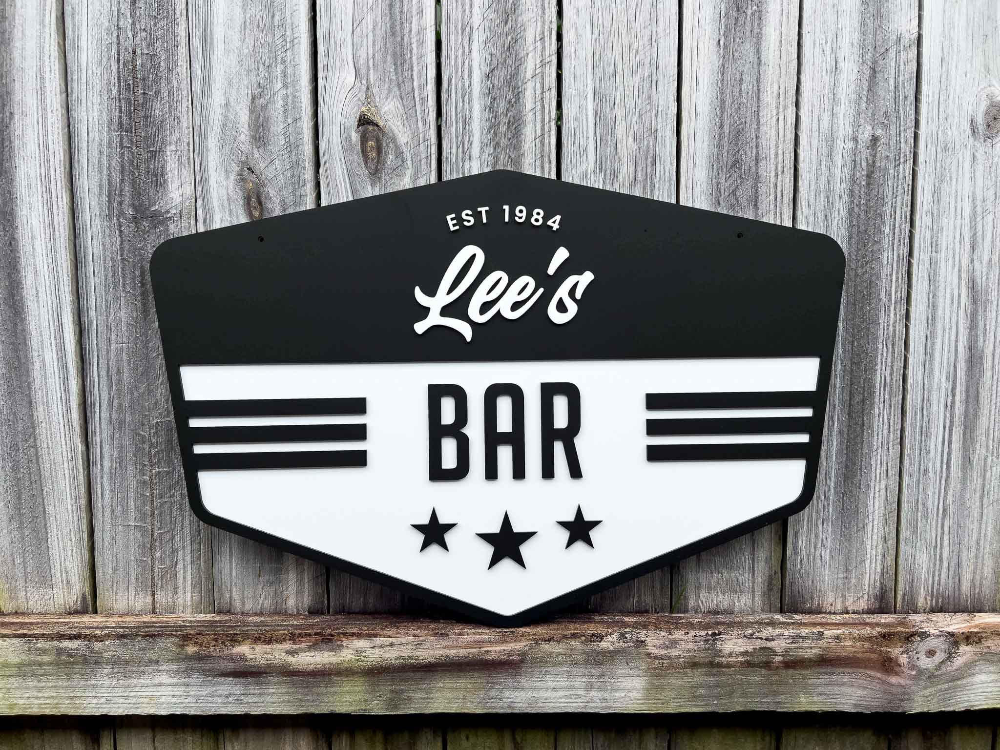 Classic custom-made vintage badge sign for 'Lee's Bar' with a black and white design on a wooden background